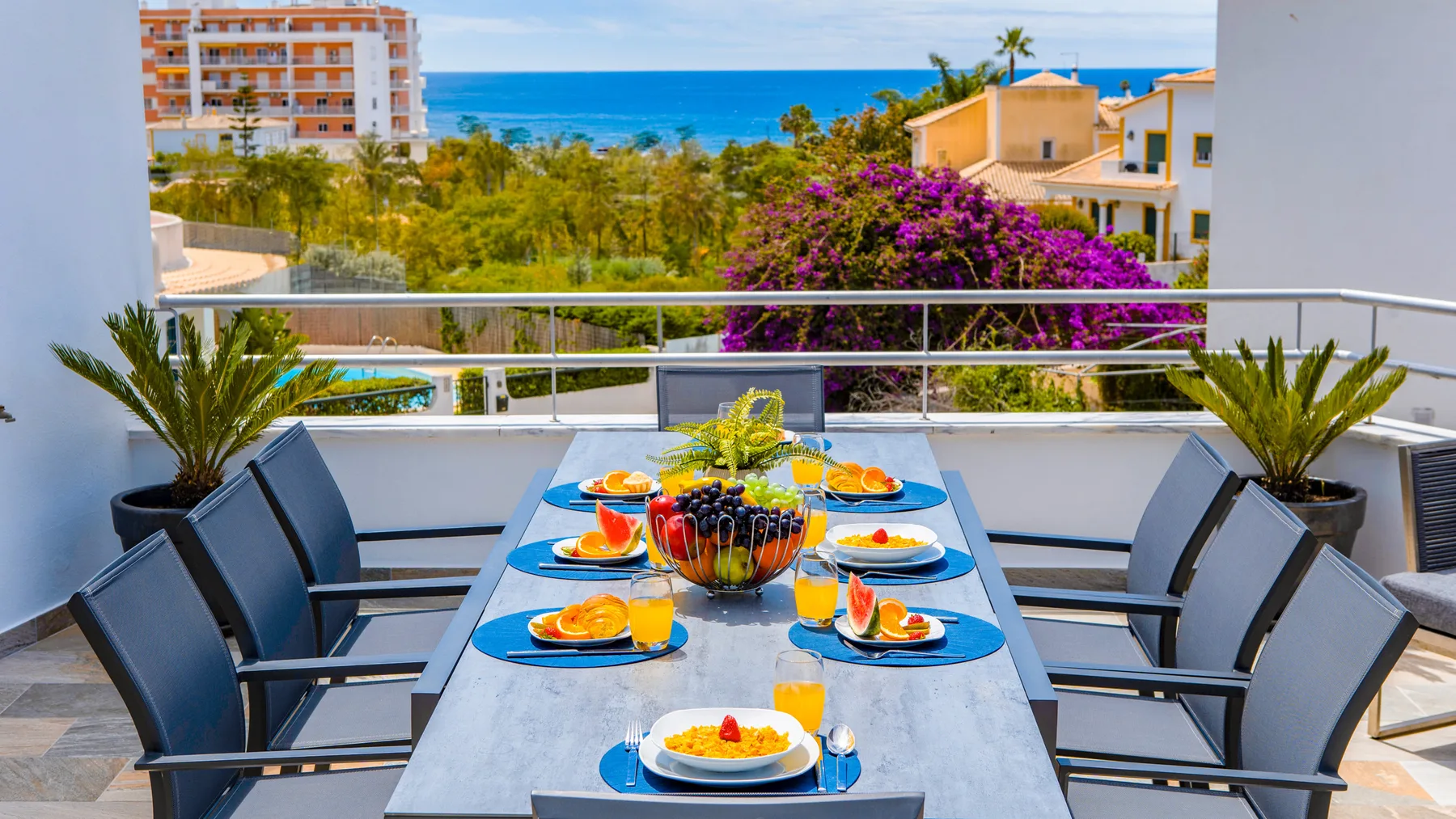 Una zona de comedor en la terraza da a jardines coloridos y al mar.
