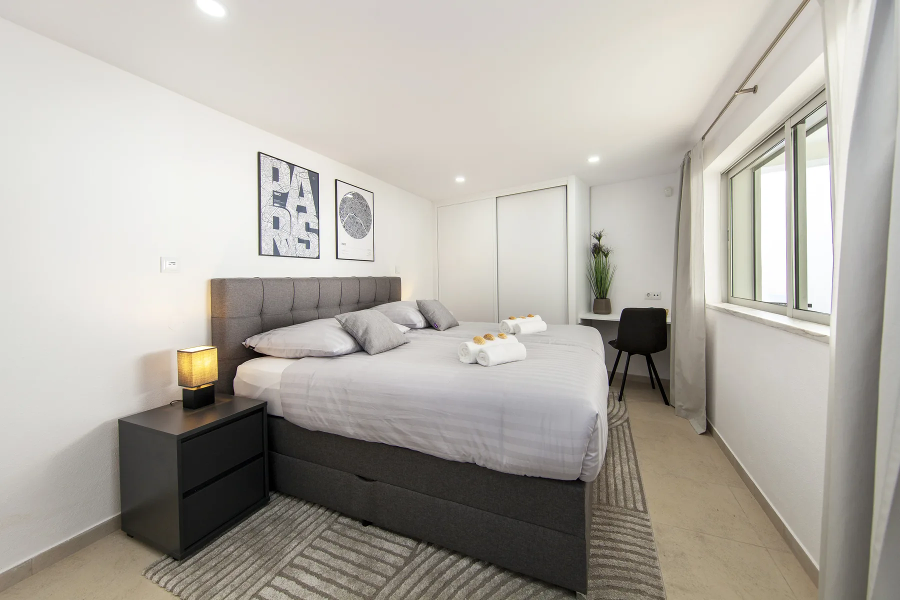Un dormitorio luminoso con una cama bien tendida y ventanas amplias.