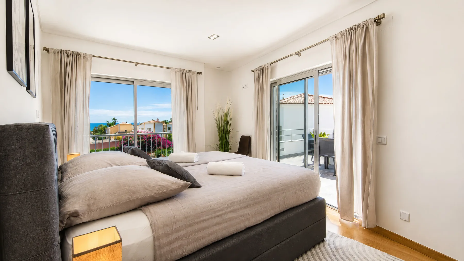 Un dormitorio con una cama grande y ventanas que dan a un balcón.