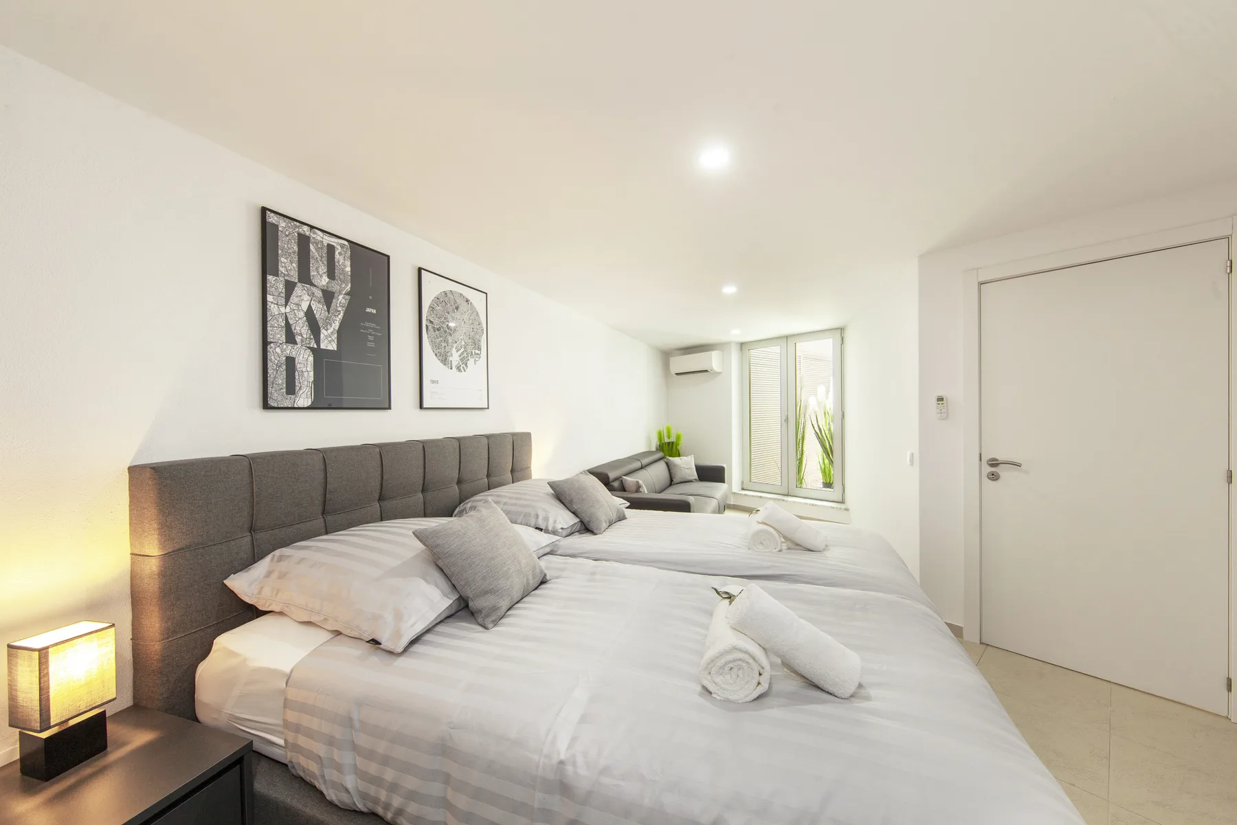 Un dormitorio luminoso con varias camas y cuadros sobre los cabeceros.