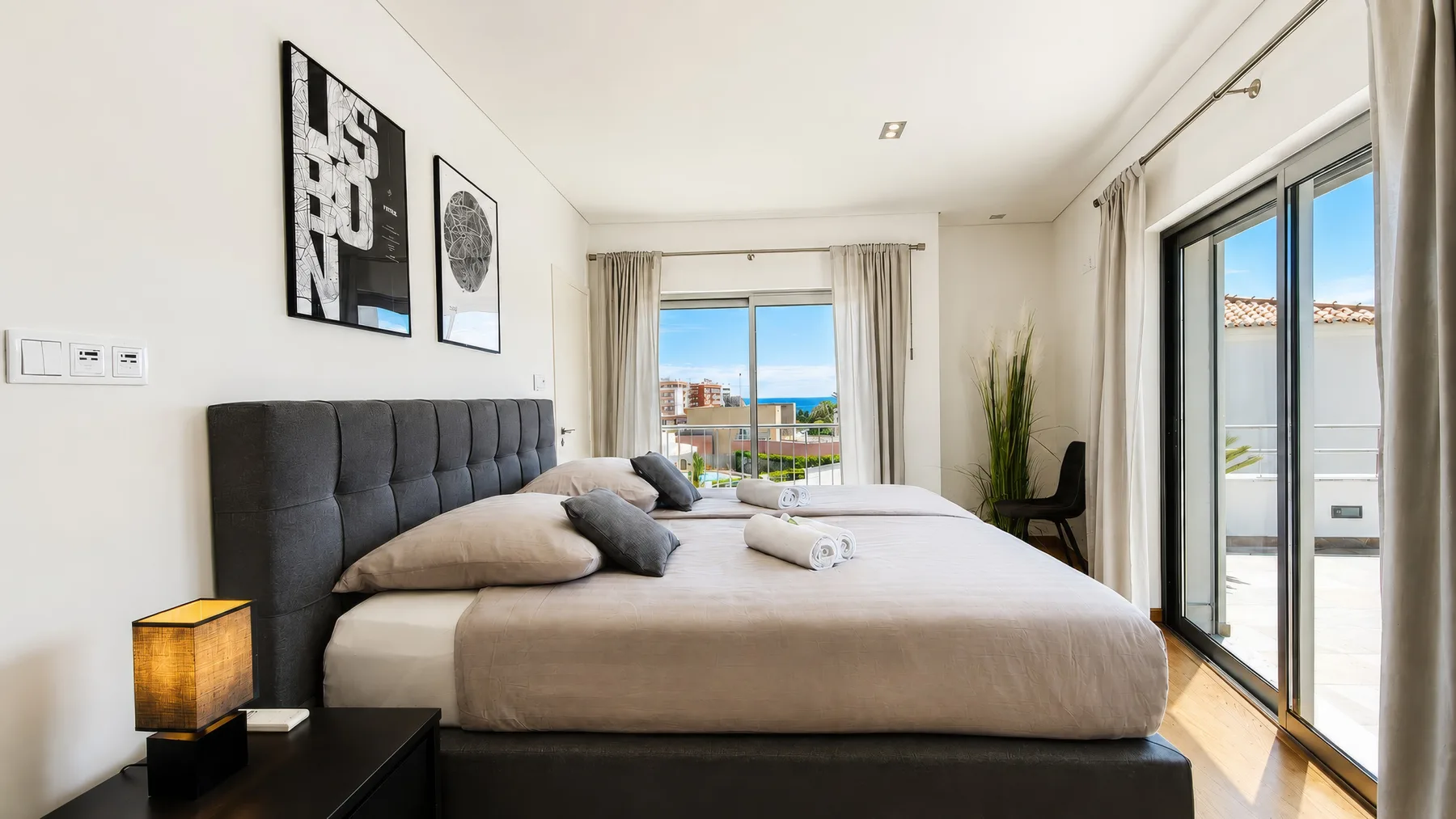 Un dormitorio luminoso con una cama grande y puertas correderas de cristal que dan a un balcón.