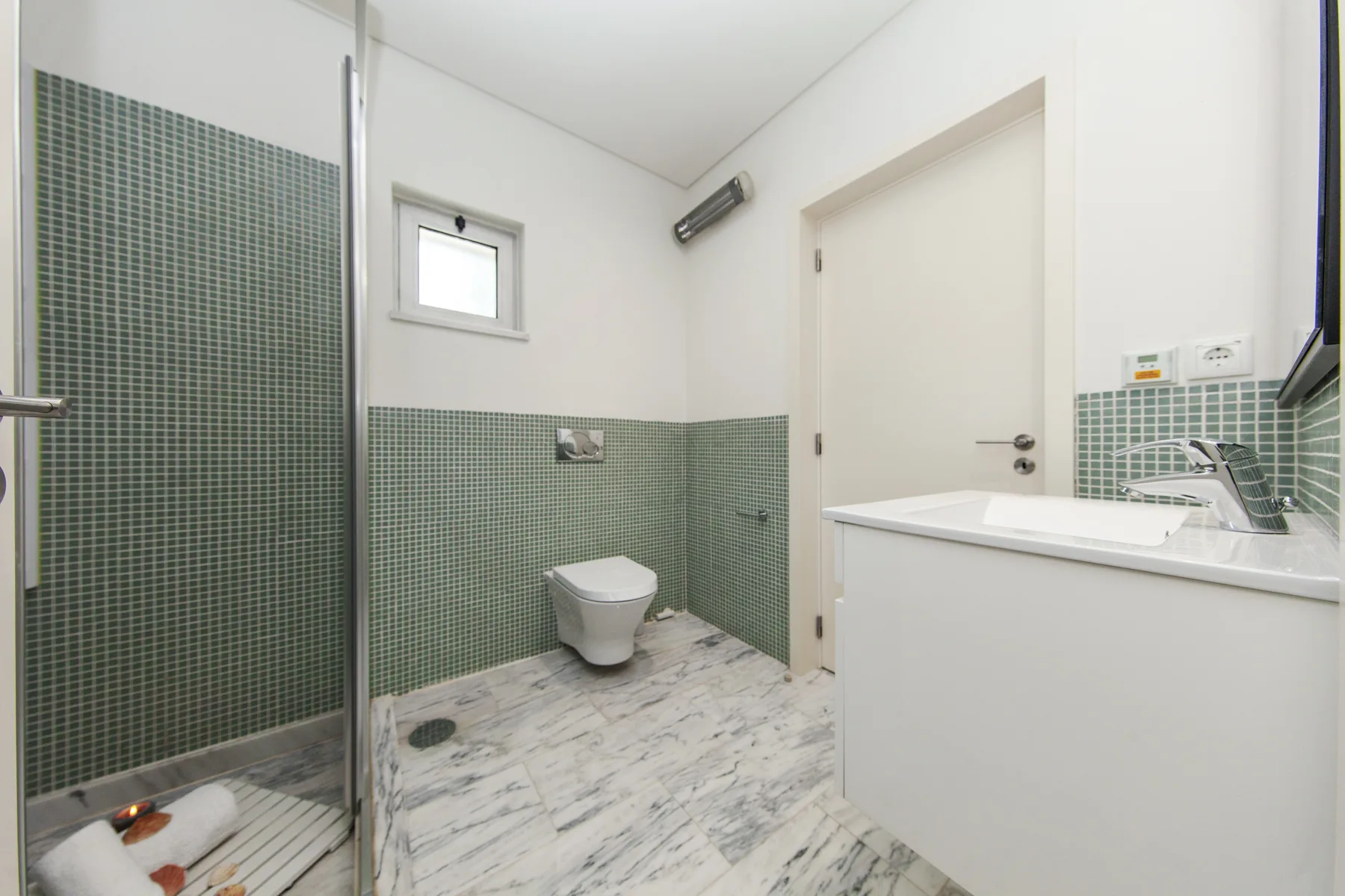 Un baño alicatado con ducha, inodoro y lavabo.