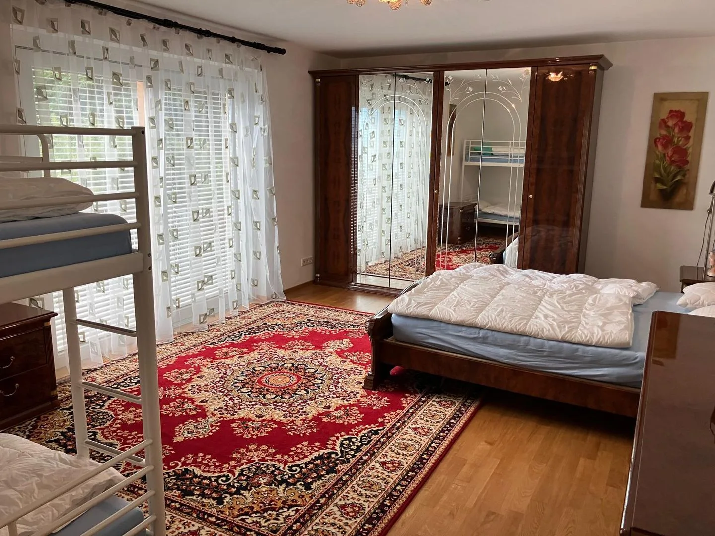 Un dormitorio con una cama grande, una alfombra estampada y un armario con espejo.