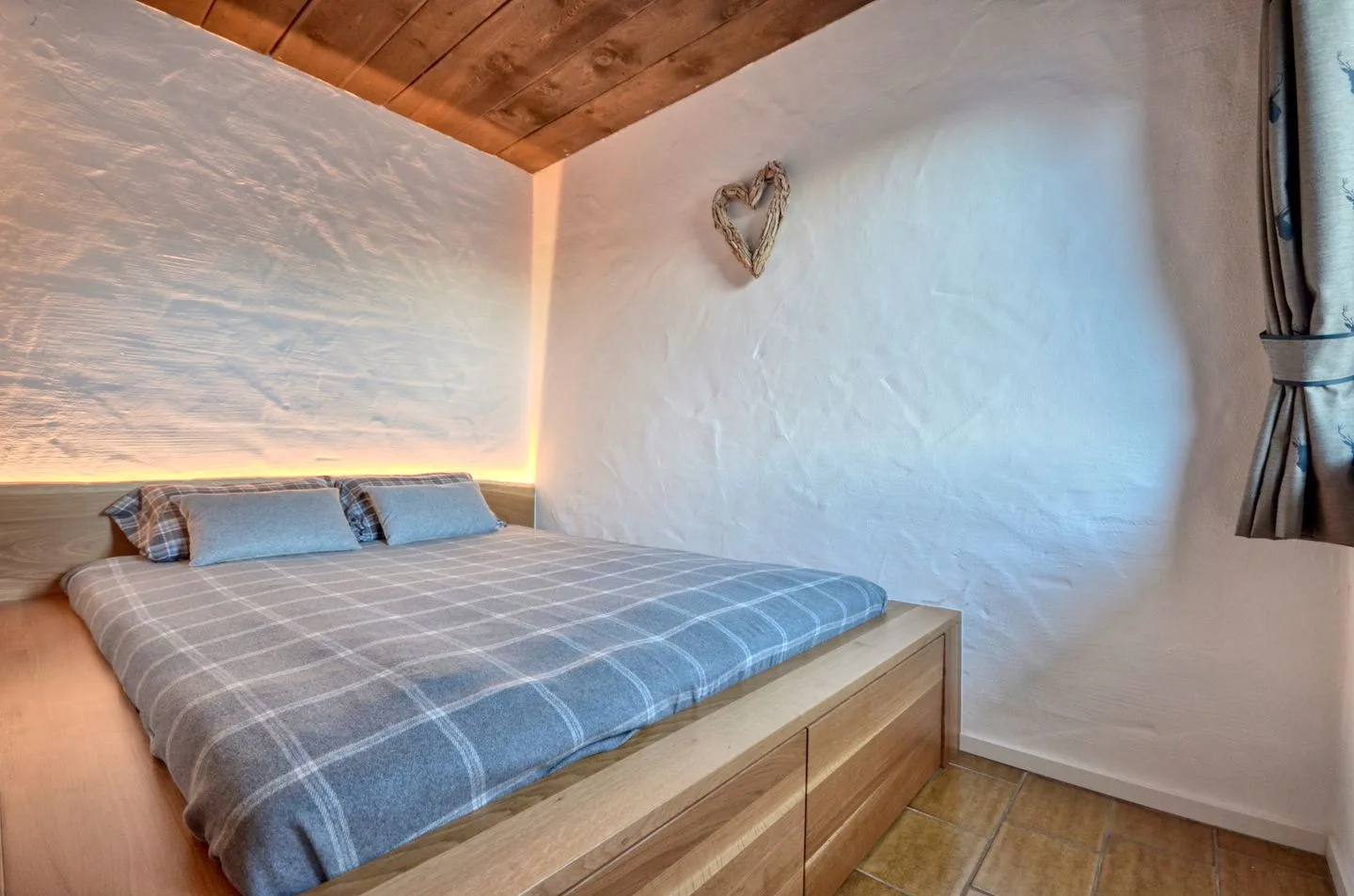 Un dormitorio con una cama baja y un pequeño adorno de pared en forma de corazón.