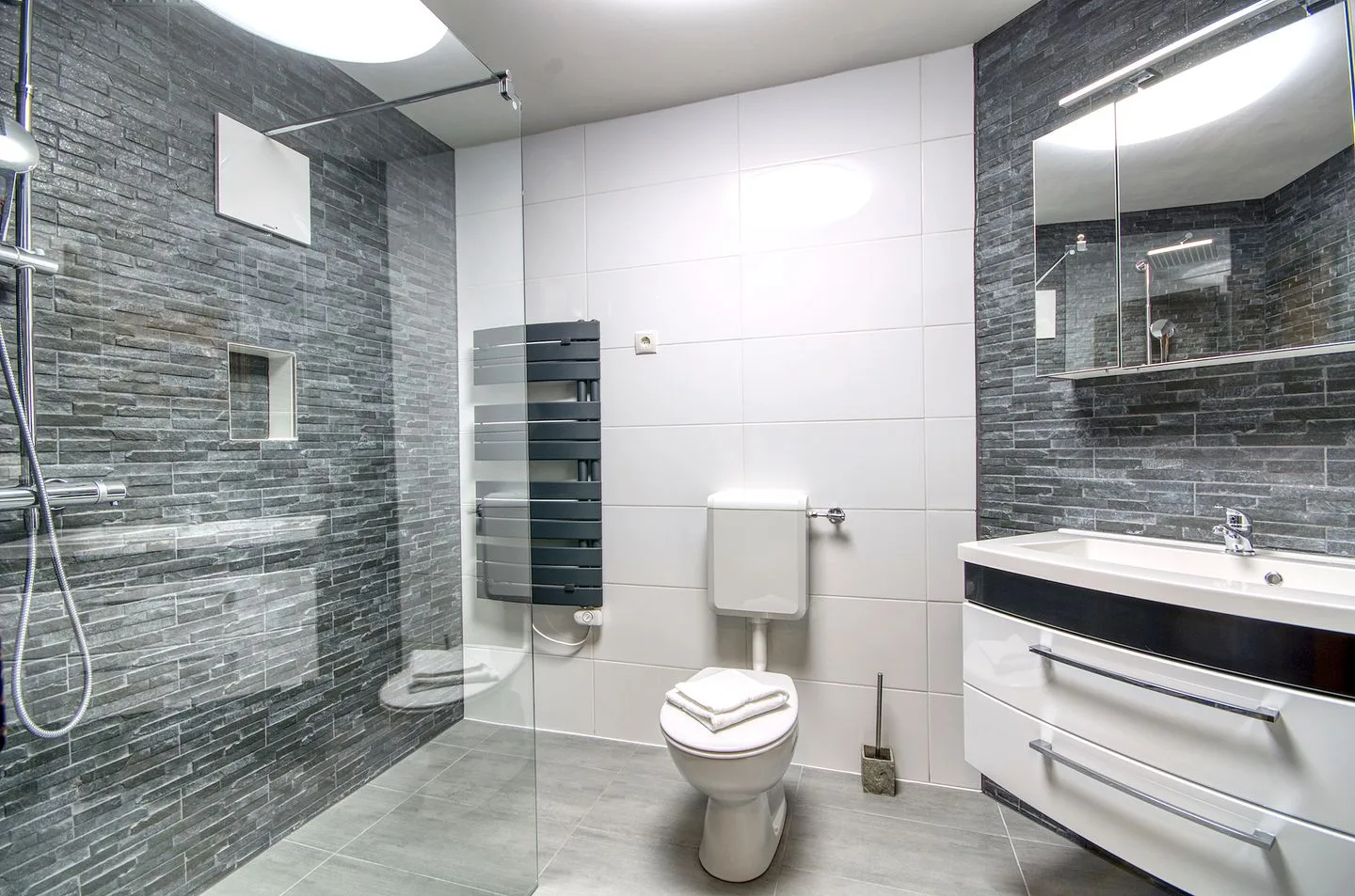 Un baño moderno con ducha de cristal, inodoro y lavabo.