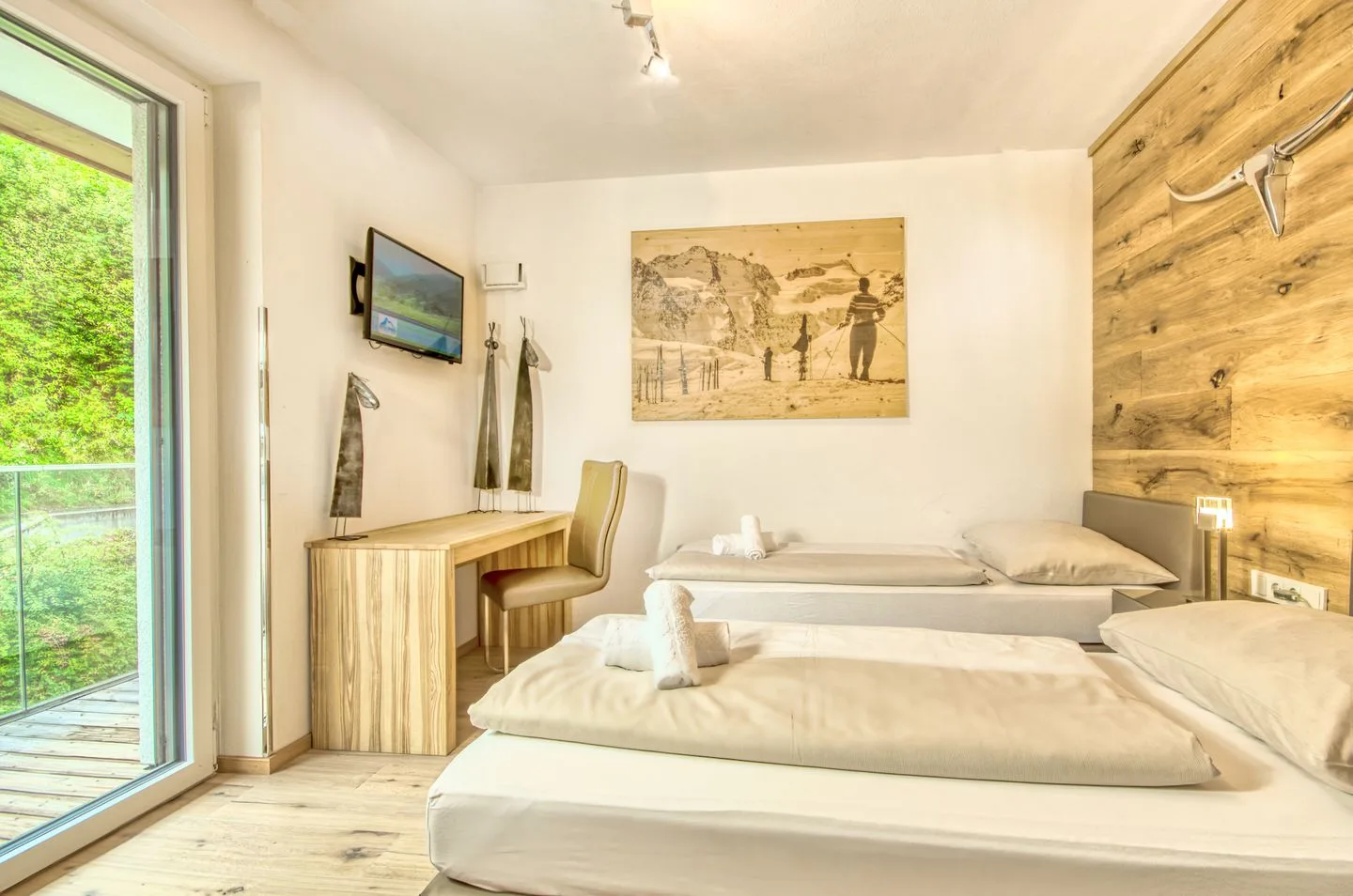 Un dormitorio luminoso con dos camas, un escritorio y un cuadro grande en la pared.
