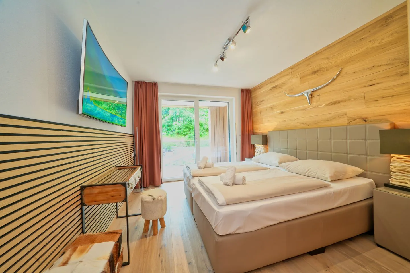 Un dormitorio con una cama grande, paneles de pared a rayas y una puerta de vidrio con vista a la vegetación.