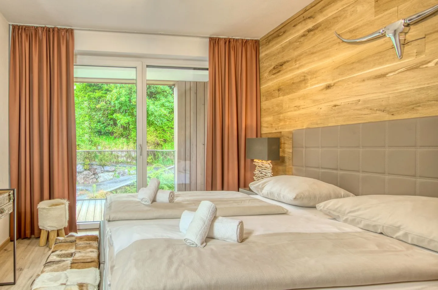 Un dormitorio con ropa de cama blanca y puertas de vidrio que dan a la vegetación.