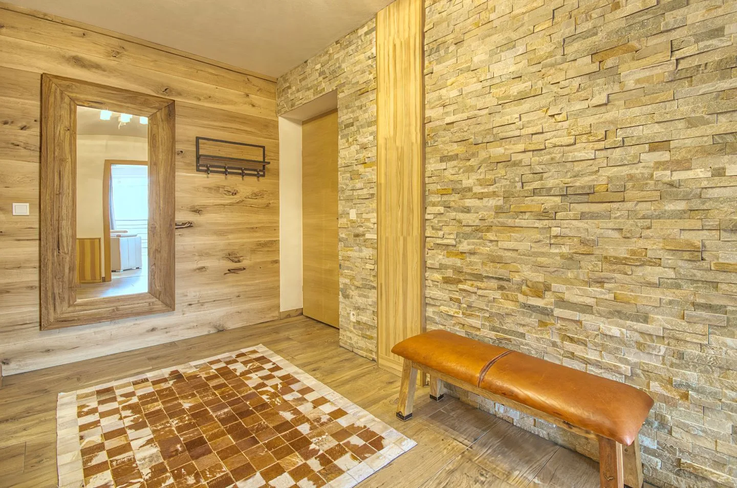 Un recibidor revestido de madera tiene una pared de piedra y un banco.