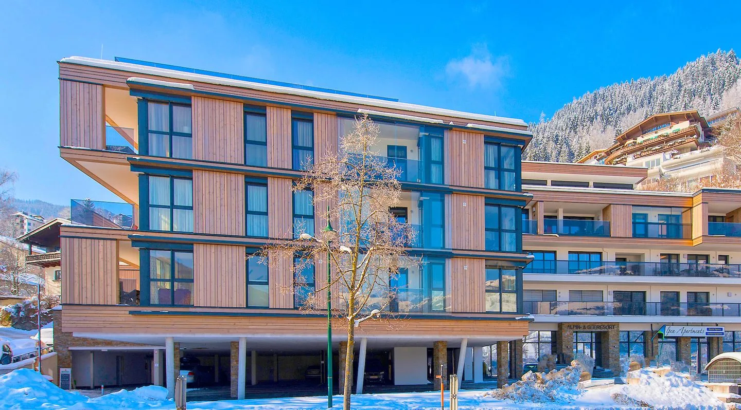 Zona común: Un edificio moderno de varios pisos se alza junto a una montaña nevada.