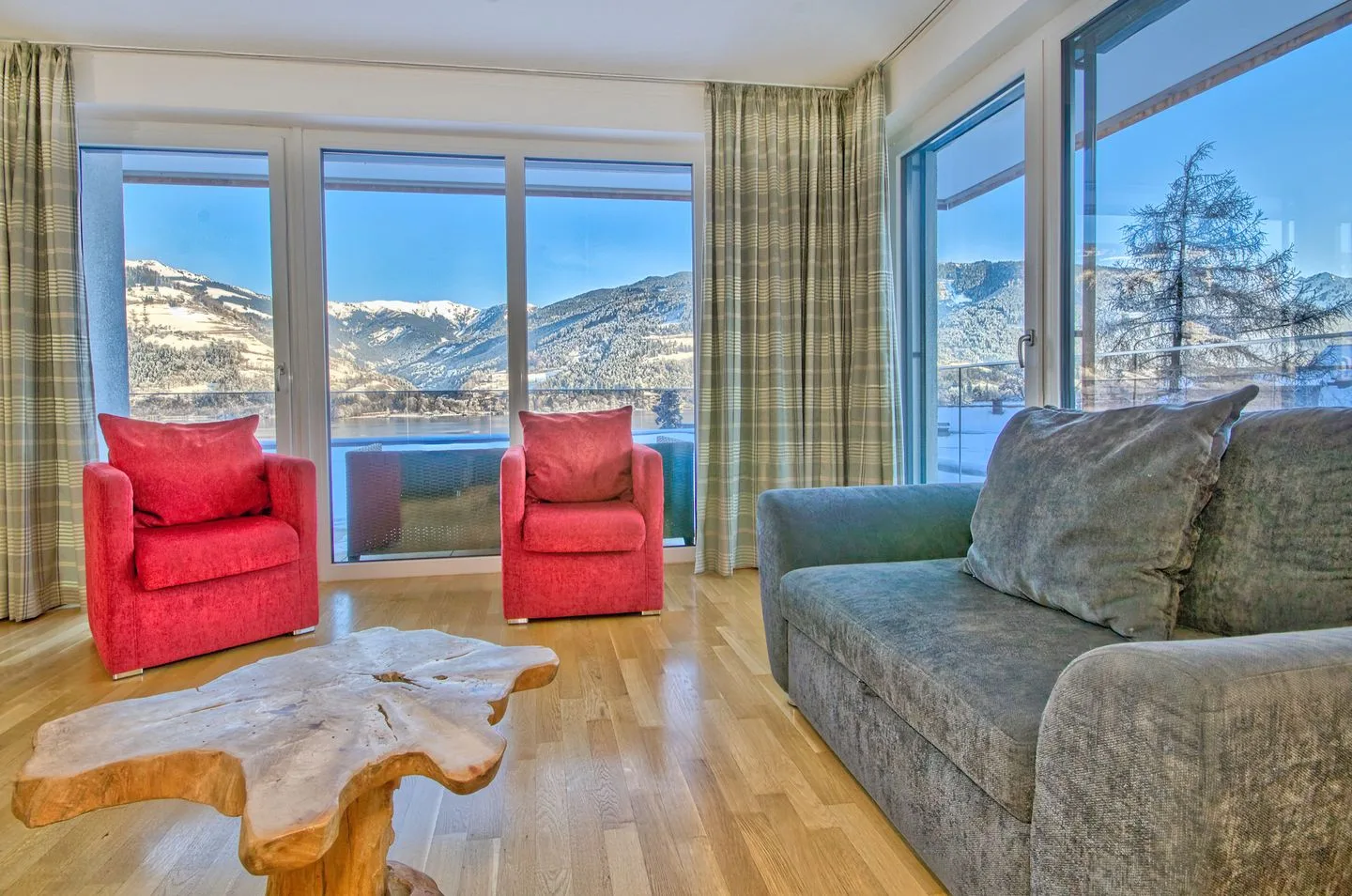 Una sala de estar con asientos y grandes ventanas con vistas a un paisaje montañoso.
