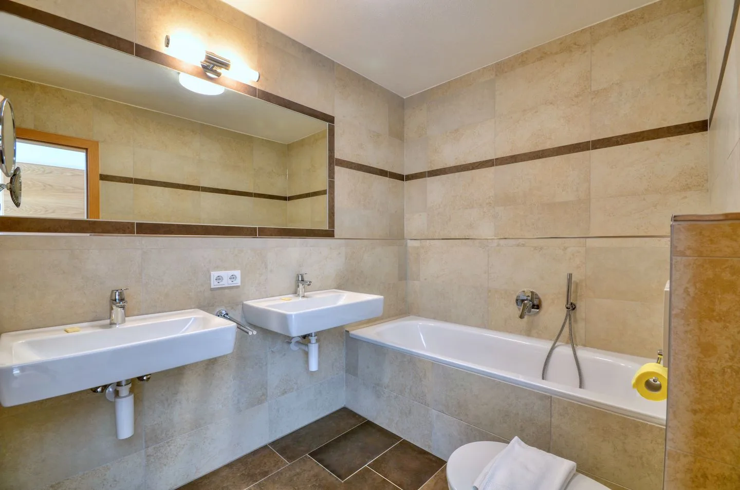 Un baño alicatado con dos lavabos, una bañera y un espejo de pared.