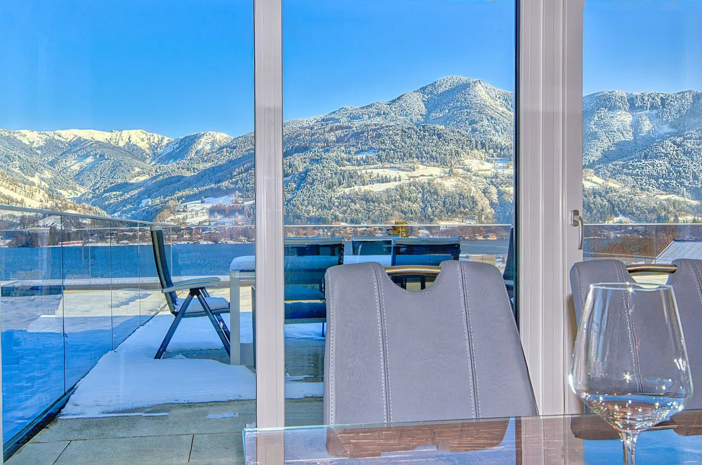 Un comedor se abre a una terraza nevada con vistas a las montañas.