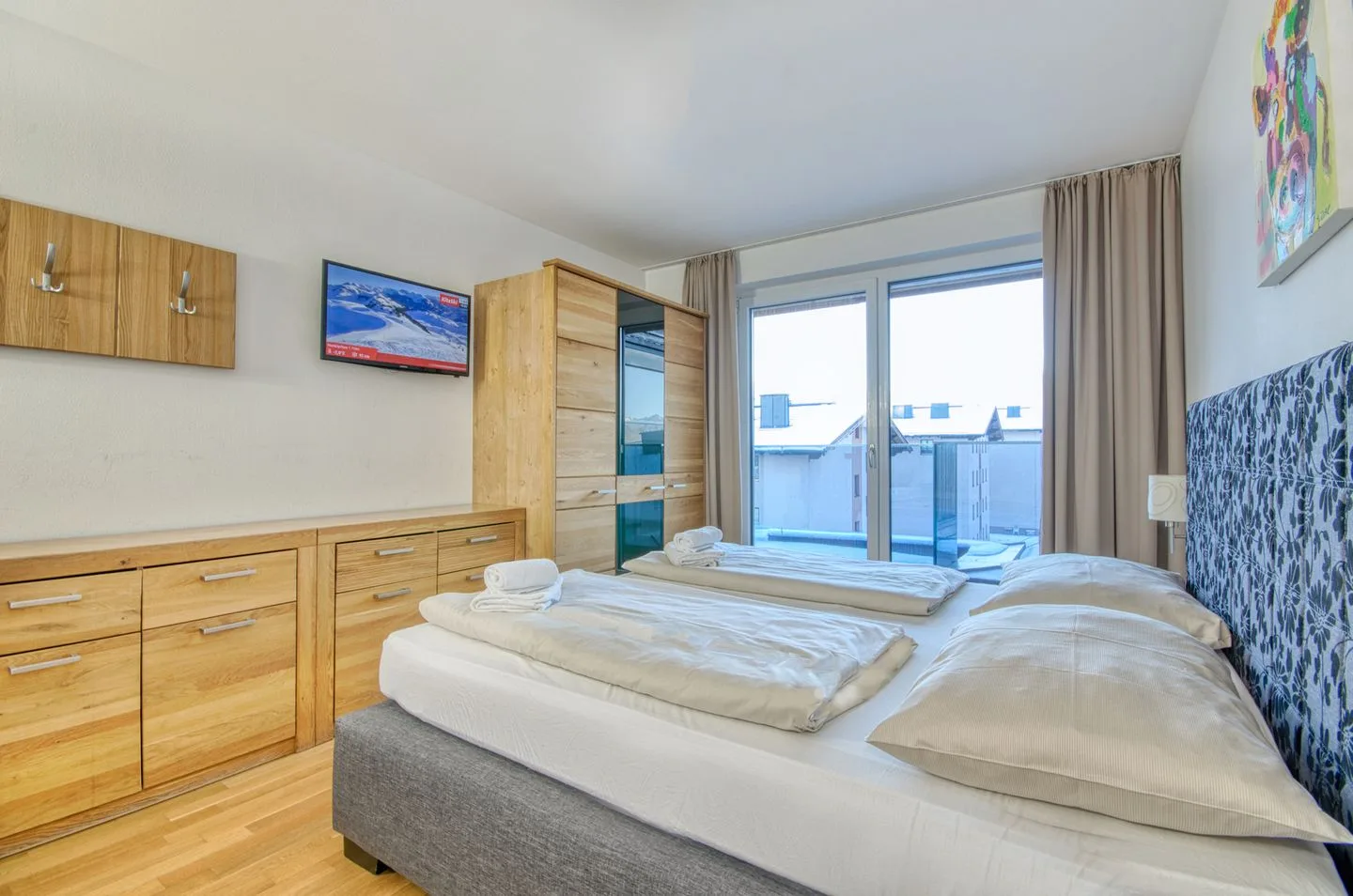 Un dormitorio con cama, armarios de madera y una puerta de vidrio que da a un balcón.