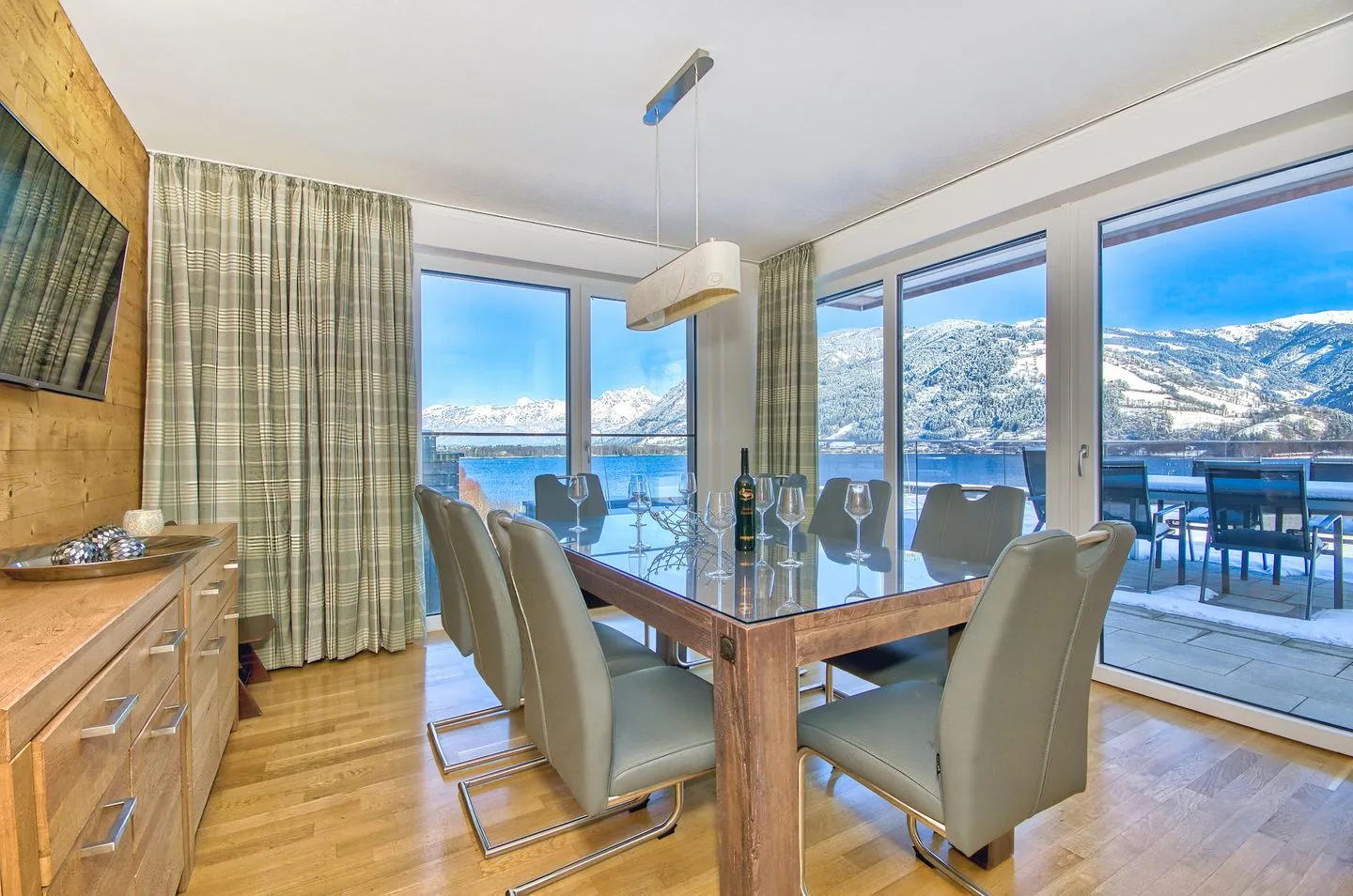 Comedor con una mesa de cristal y grandes ventanales con vistas a un paisaje nevado.