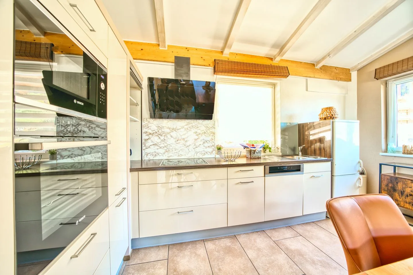 A bright modern kitchen with white cabinets and a marble-patterned backsplash.