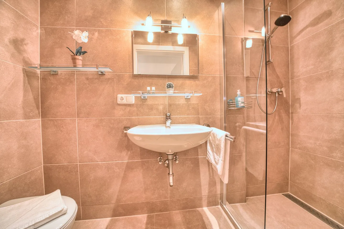 A tiled bathroom with a sink, mirror, and shower.