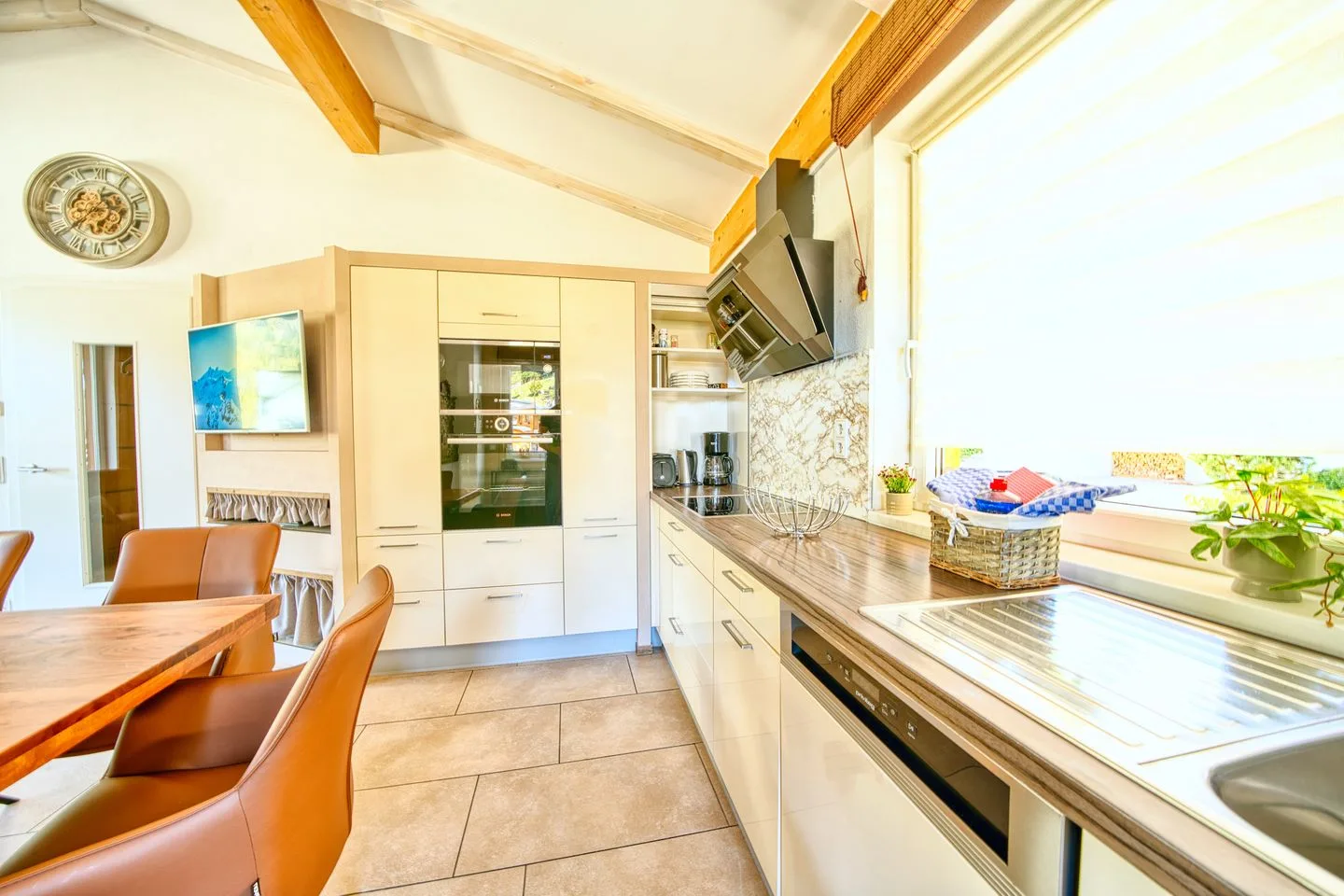 A bright kitchen with a dining table and a long countertop.