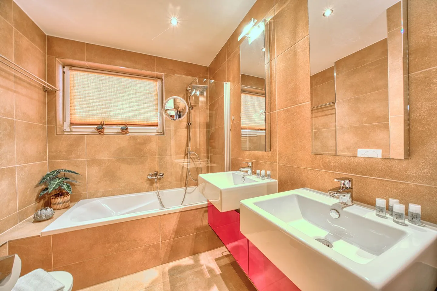 A tiled bathroom with a bathtub, shower, and two sinks.