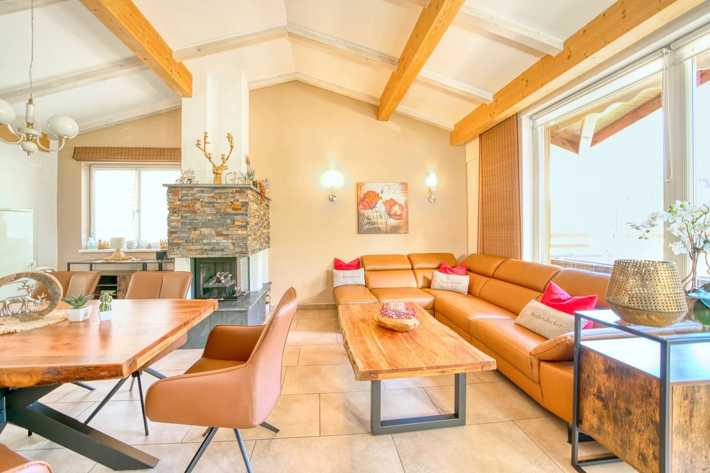 A bright living and dining area has a large sectional seating area beside a wooden table.