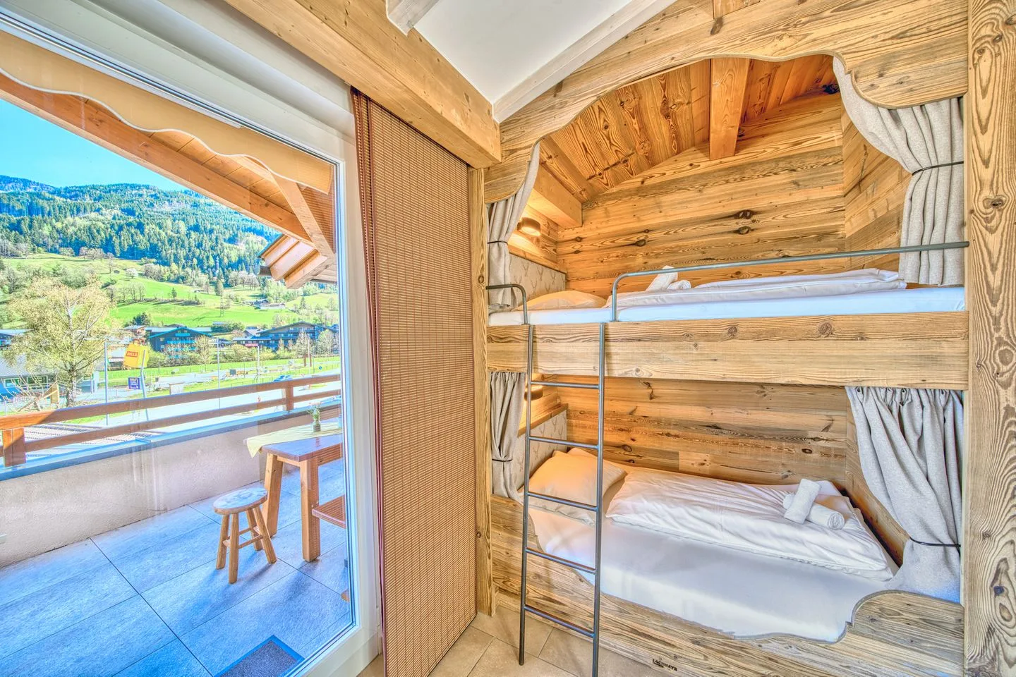 A wooden bunk-bed sleeping area beside a glass door opening onto a balcony.
