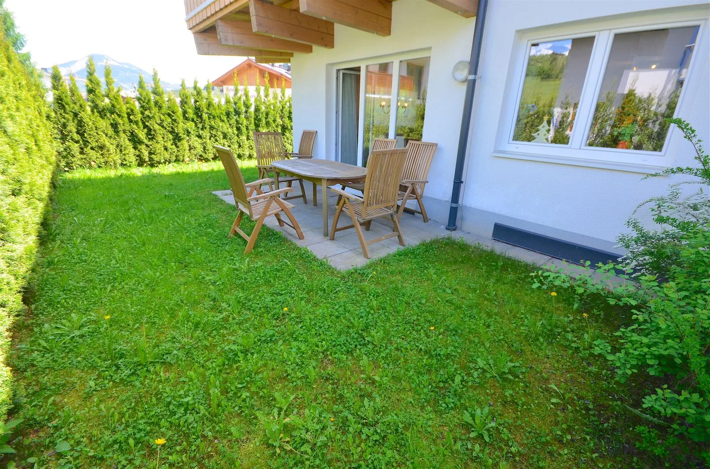 Un patio ajardinado con césped y asientos al aire libre junto a una casa.