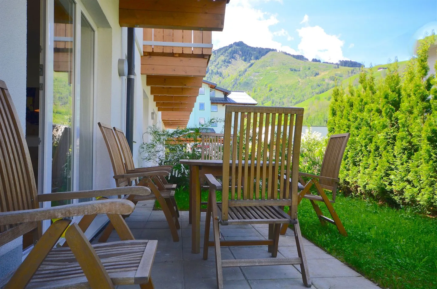 Un patio al aire libre con asientos de madera tiene vistas a una colina verde.