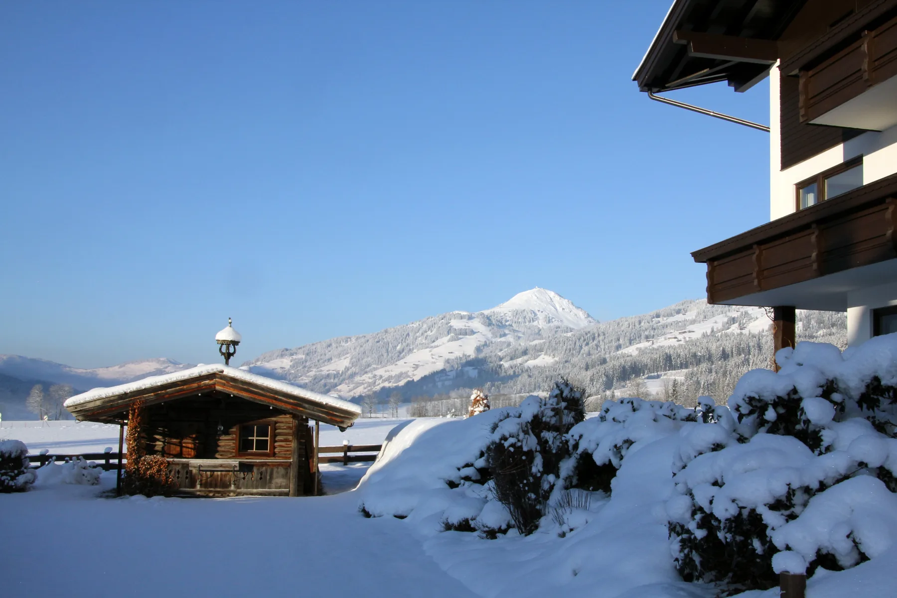 Zona común: Una escena exterior cubierta de nieve, con una cabaña de madera y montañas al fondo.