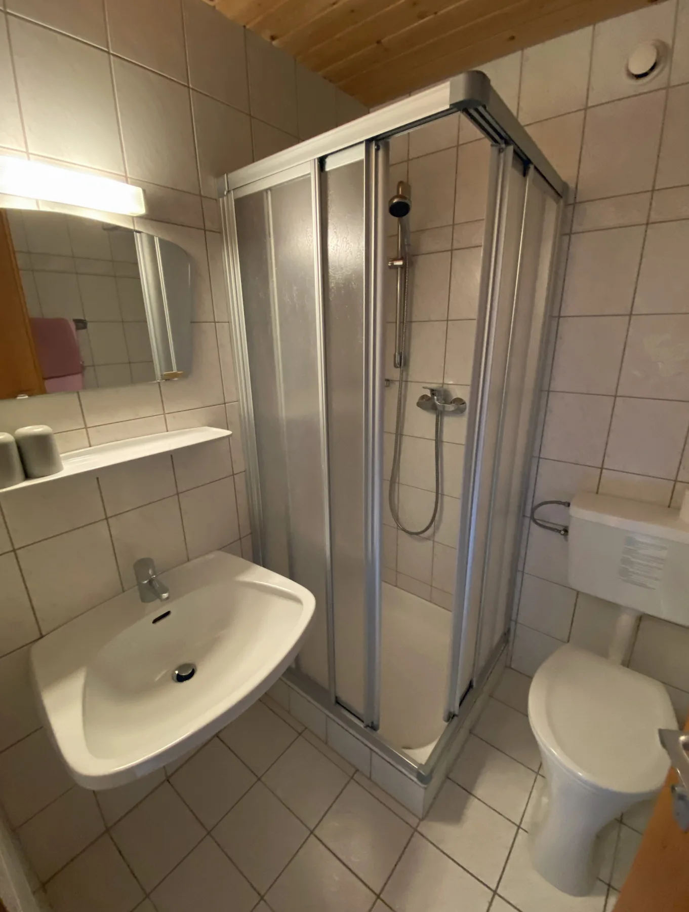 Un baño alicatado con lavabo, ducha e inodoro.
