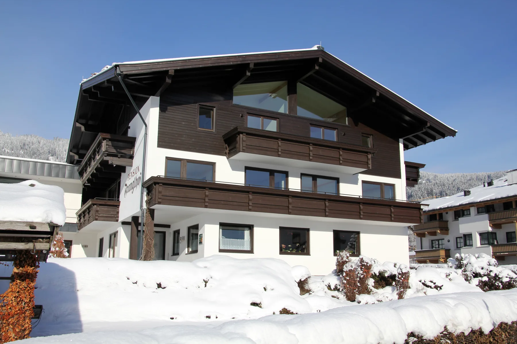 Zona común: Un edificio de estilo chalet de varias plantas se alza entre la nieve bajo un cielo despejado.