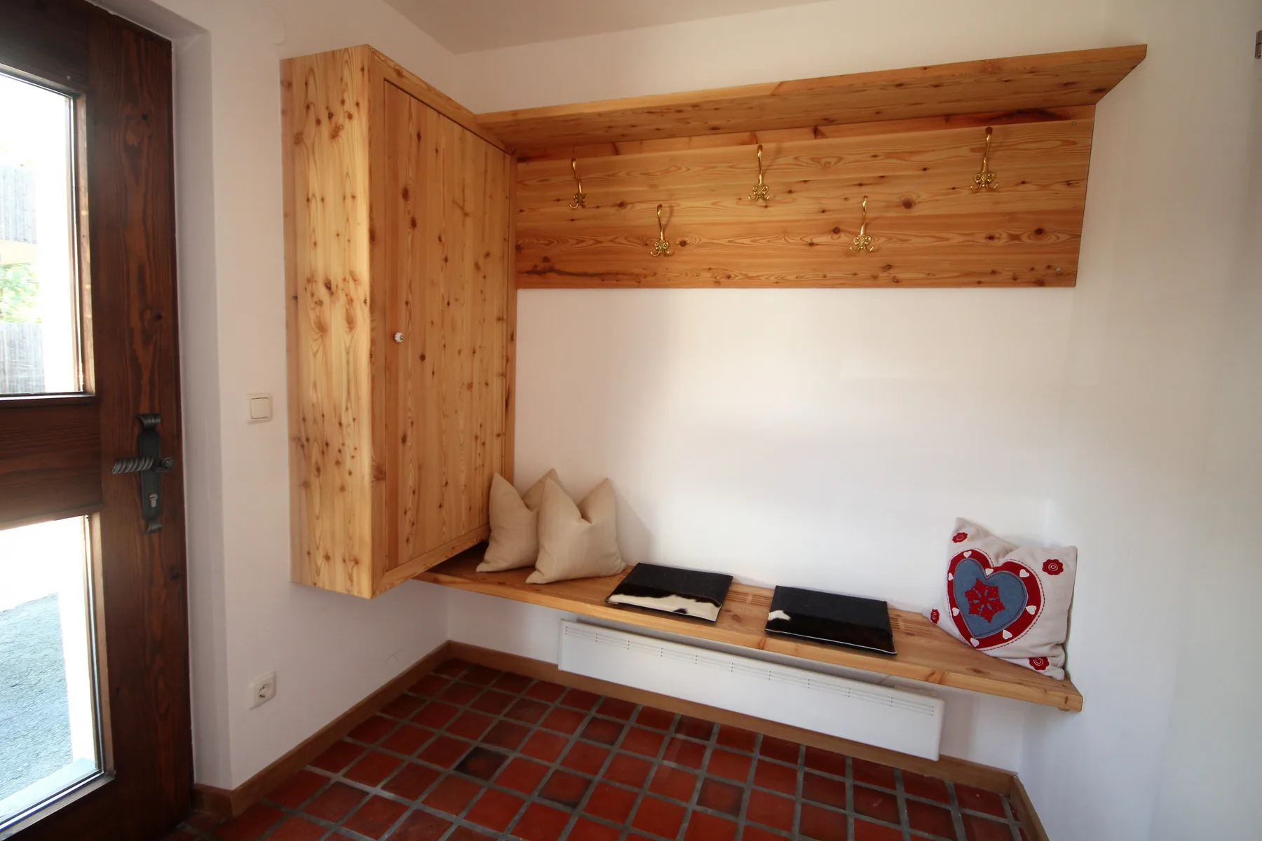 A small entry area has a built-in wooden bench beneath a row of hooks.