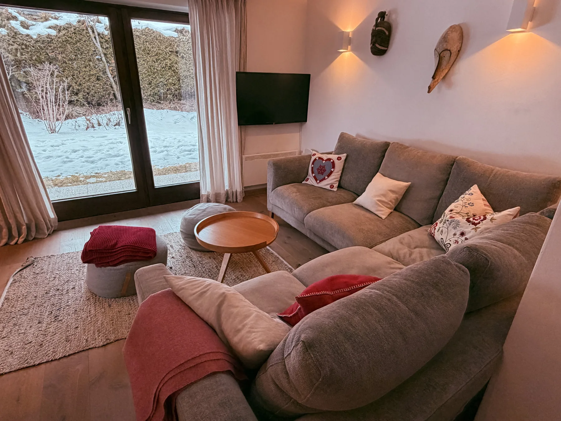A living room with sectional seating, a coffee table, and windows overlooking snow.