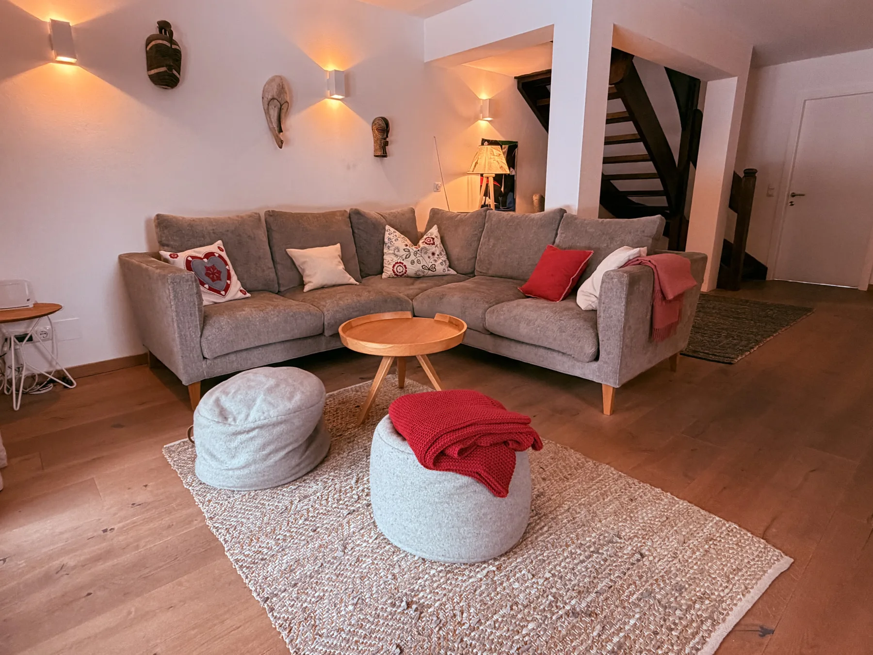 A living room with a gray sectional, round coffee table, and woven rug.