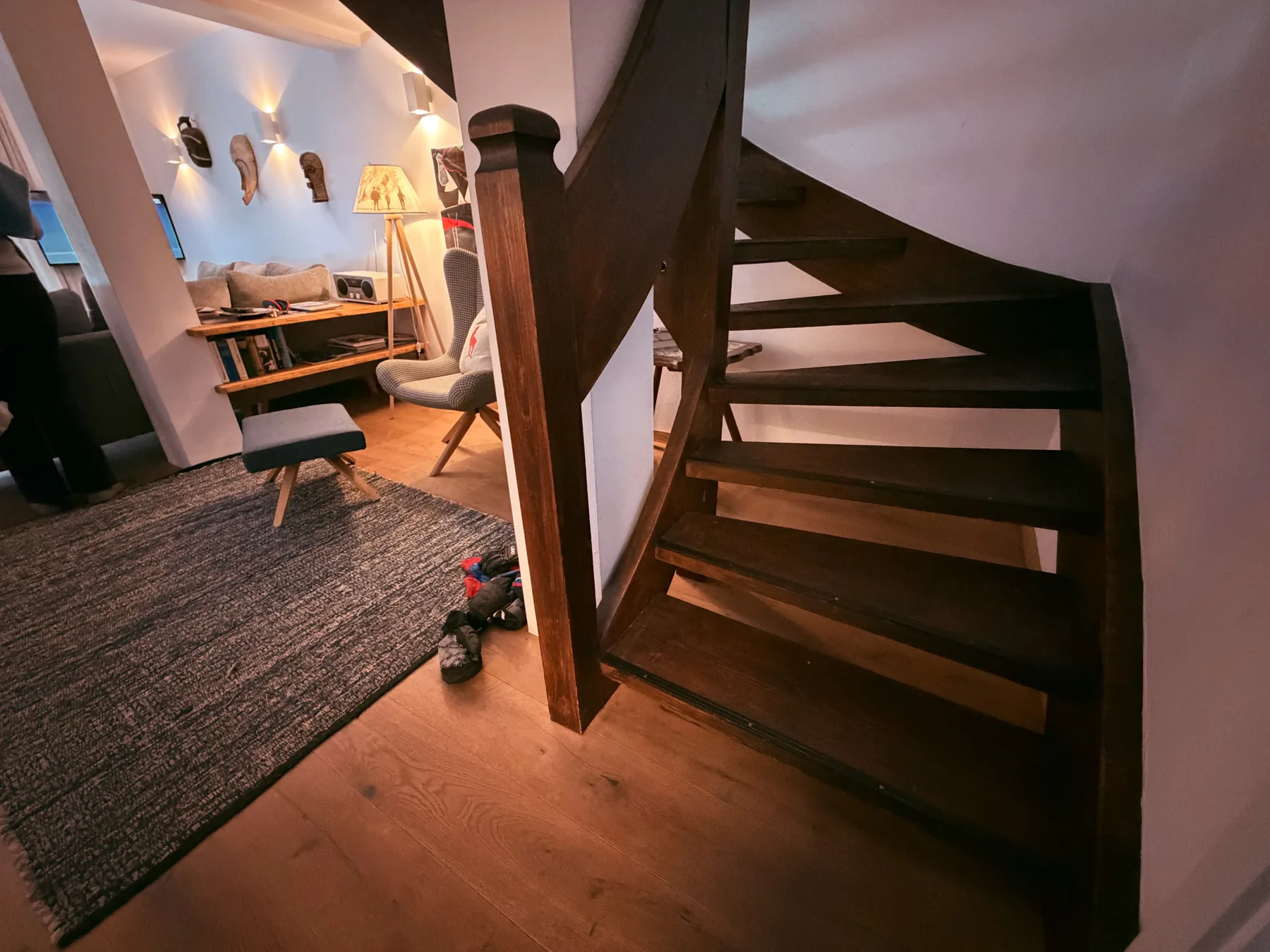 A living area with a dark wooden staircase and seating.