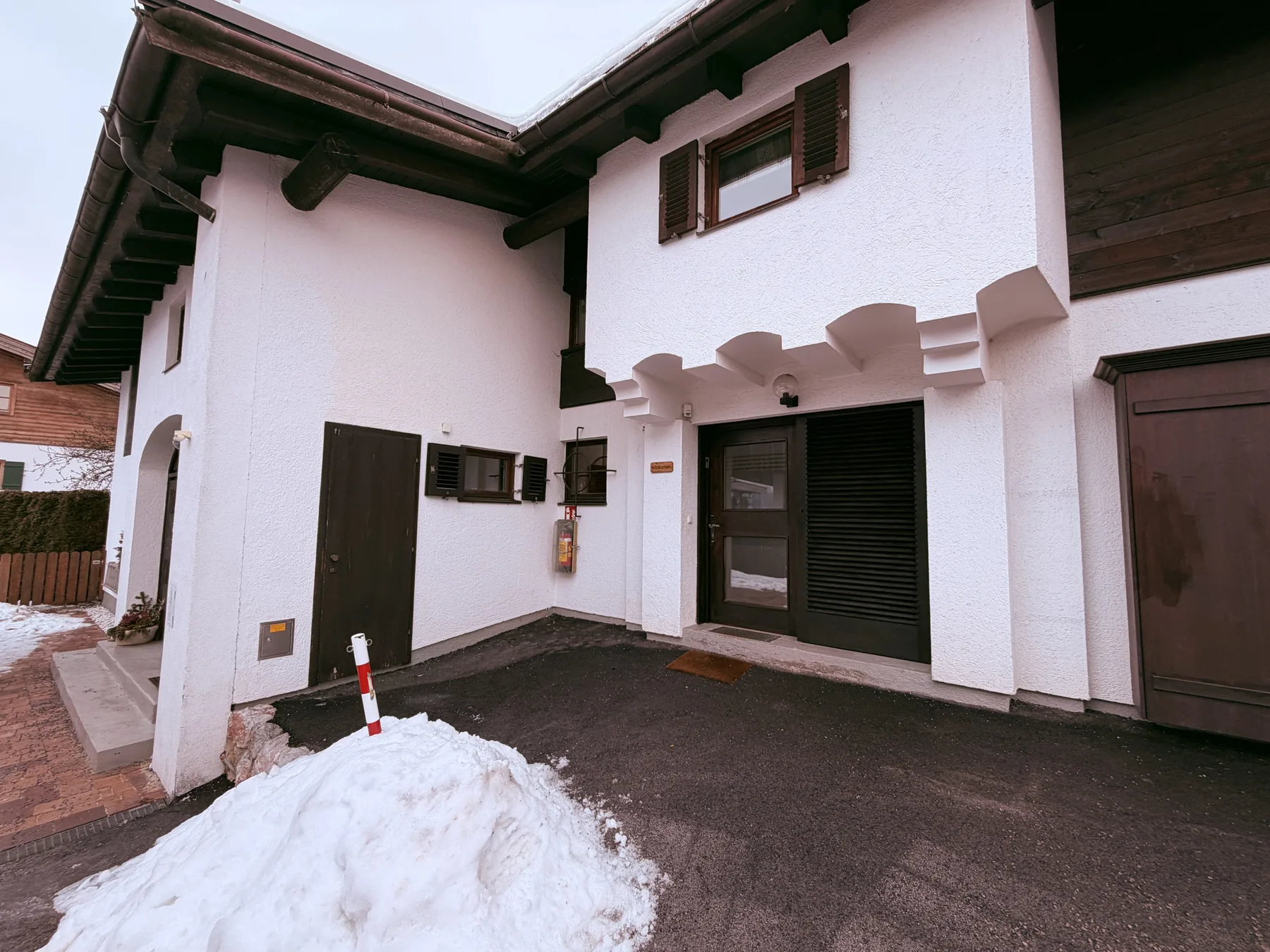 Shared amenity: Exterior of a white building with dark doors and a small pile of snow.