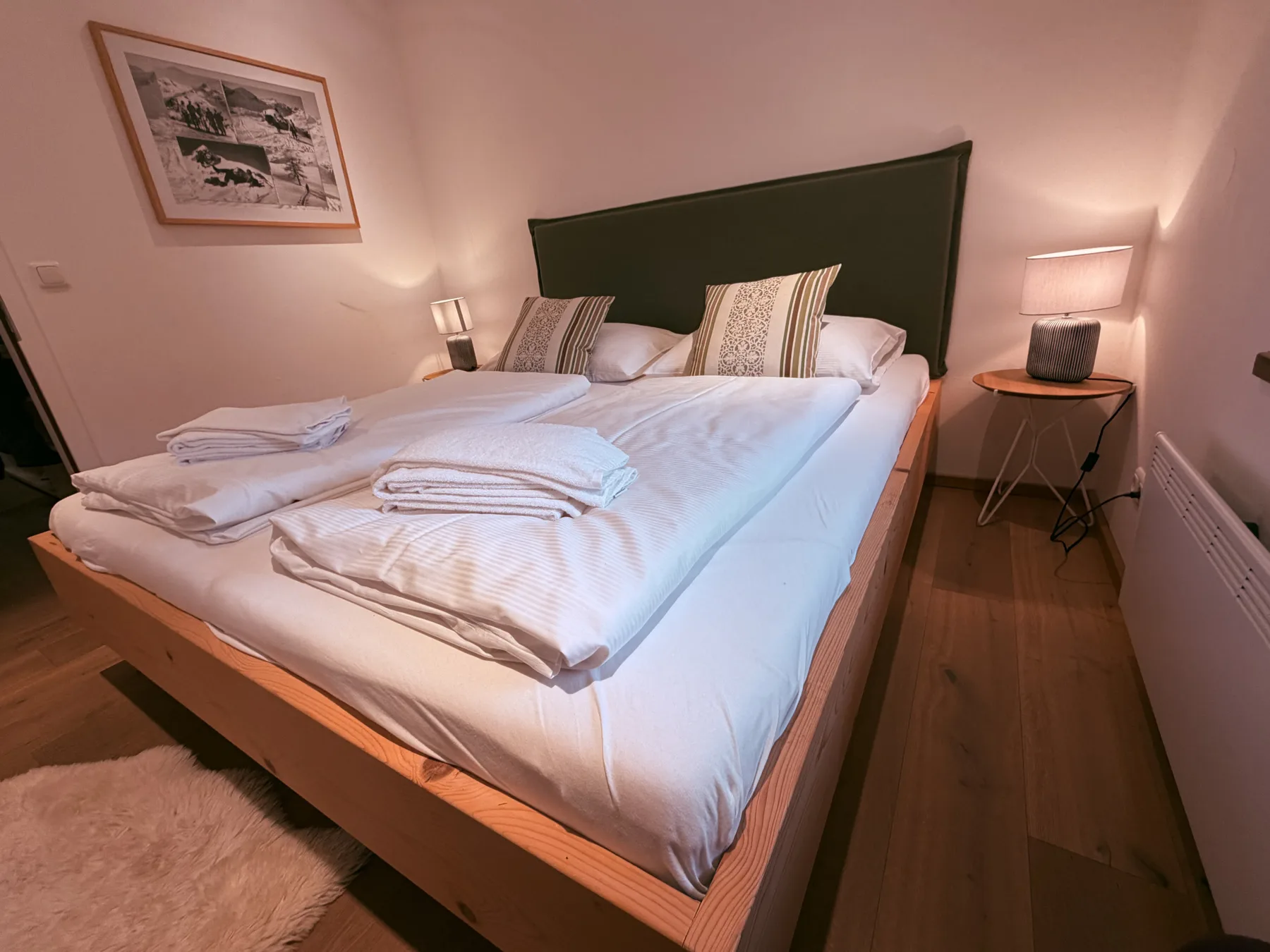 A bedroom with a neatly made bed and matching bedside lamps.
