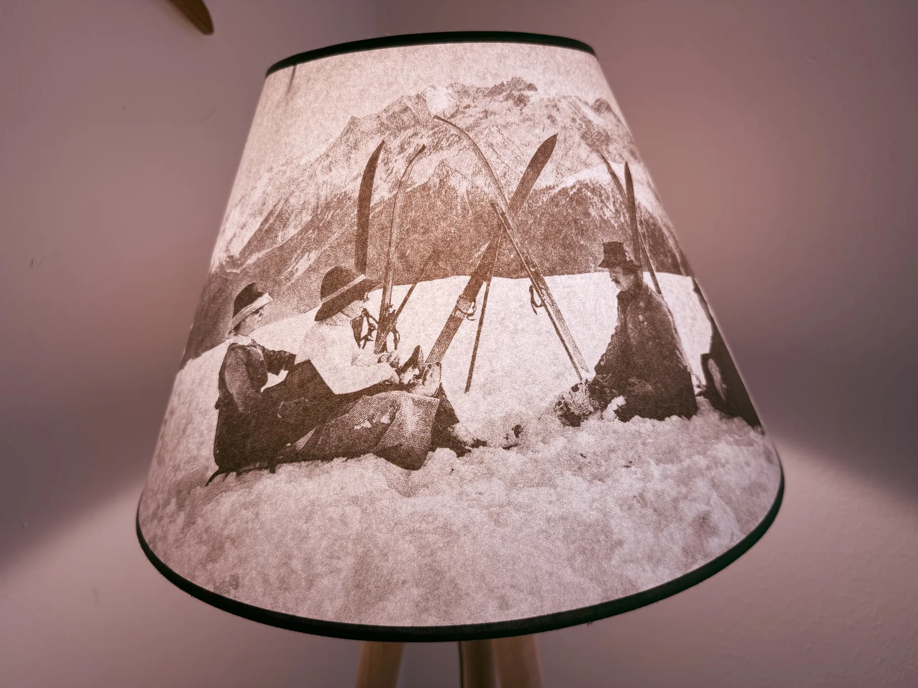 A lampshade printed with a monochrome winter scene of people skiing in the snow.