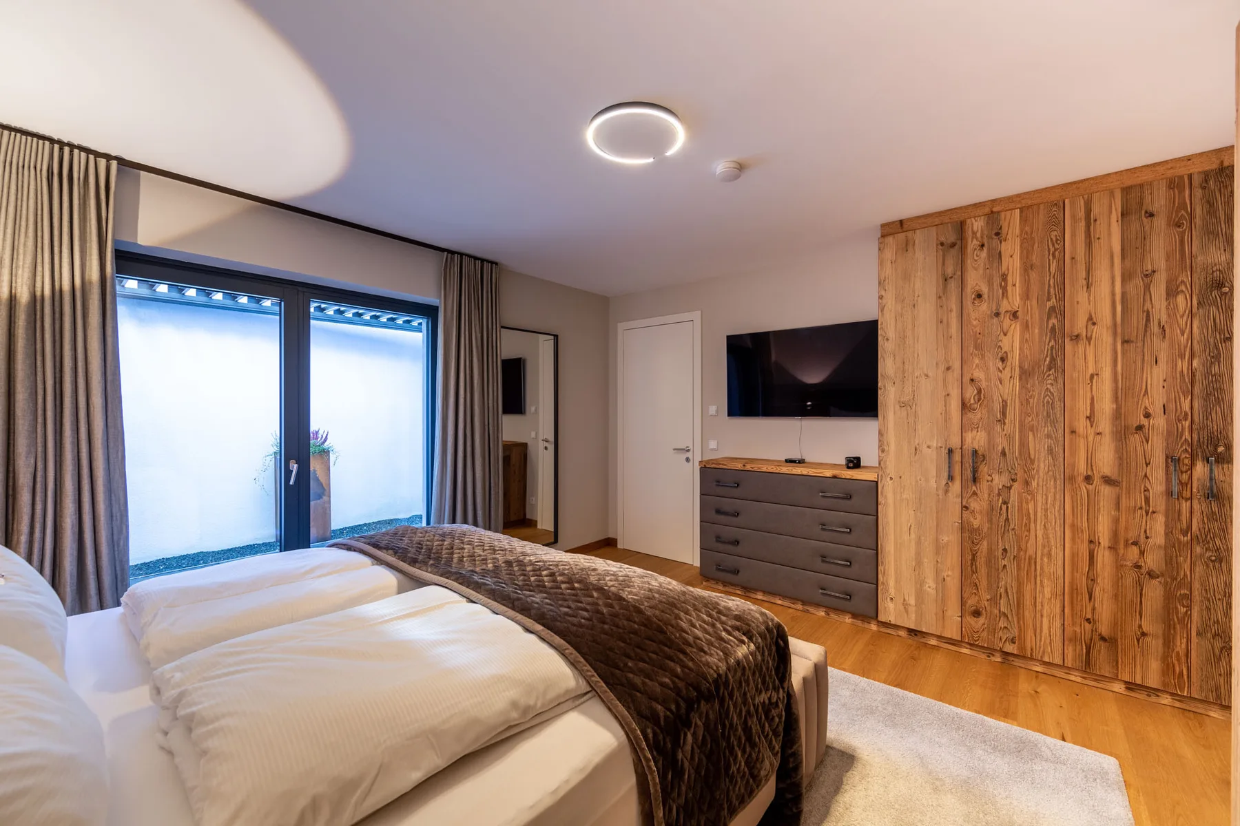 A bedroom with a bed, sliding glass doors, and a television on a dresser.