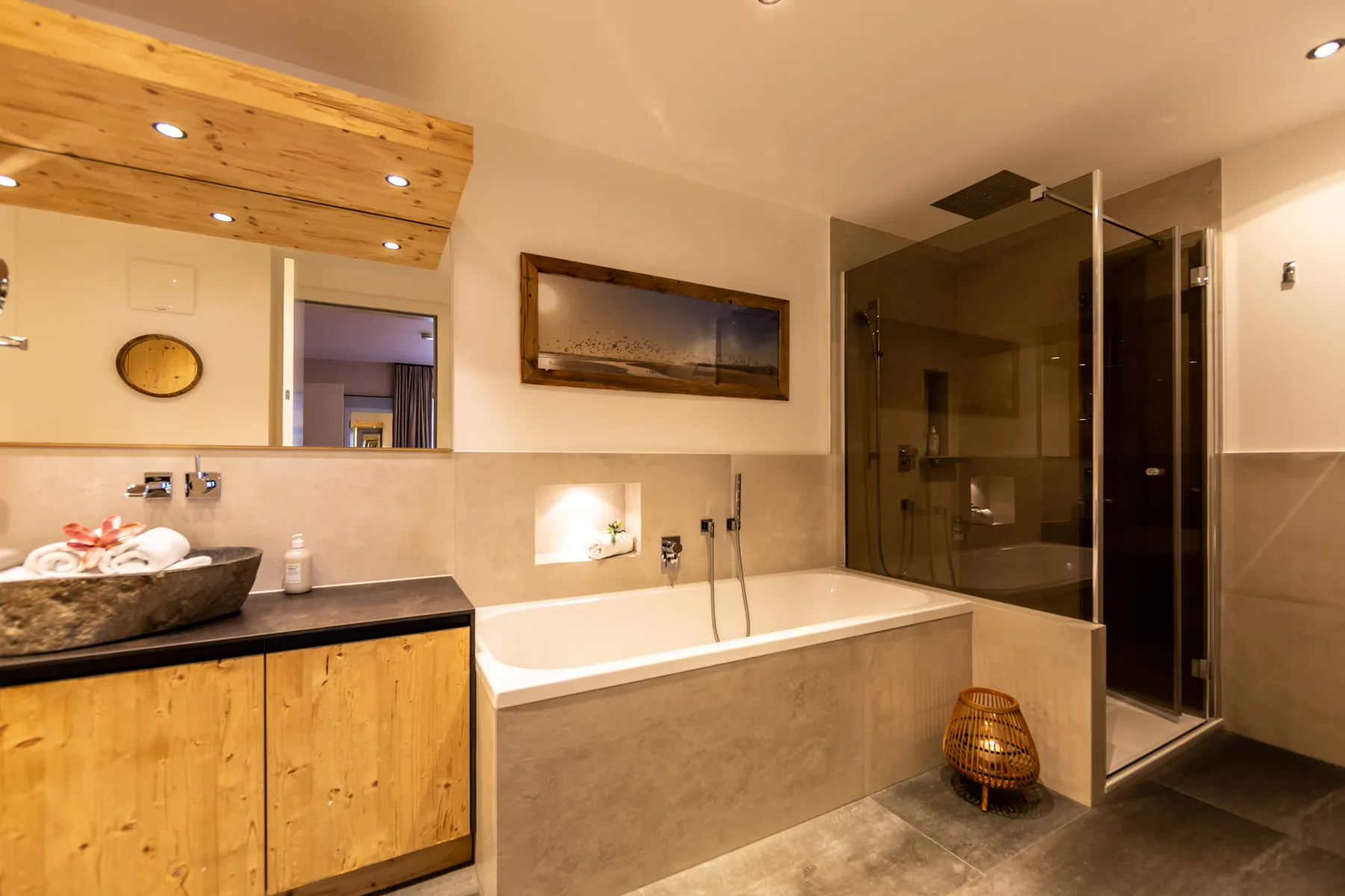 A warm-toned bathroom with a bathtub and glass-enclosed shower.