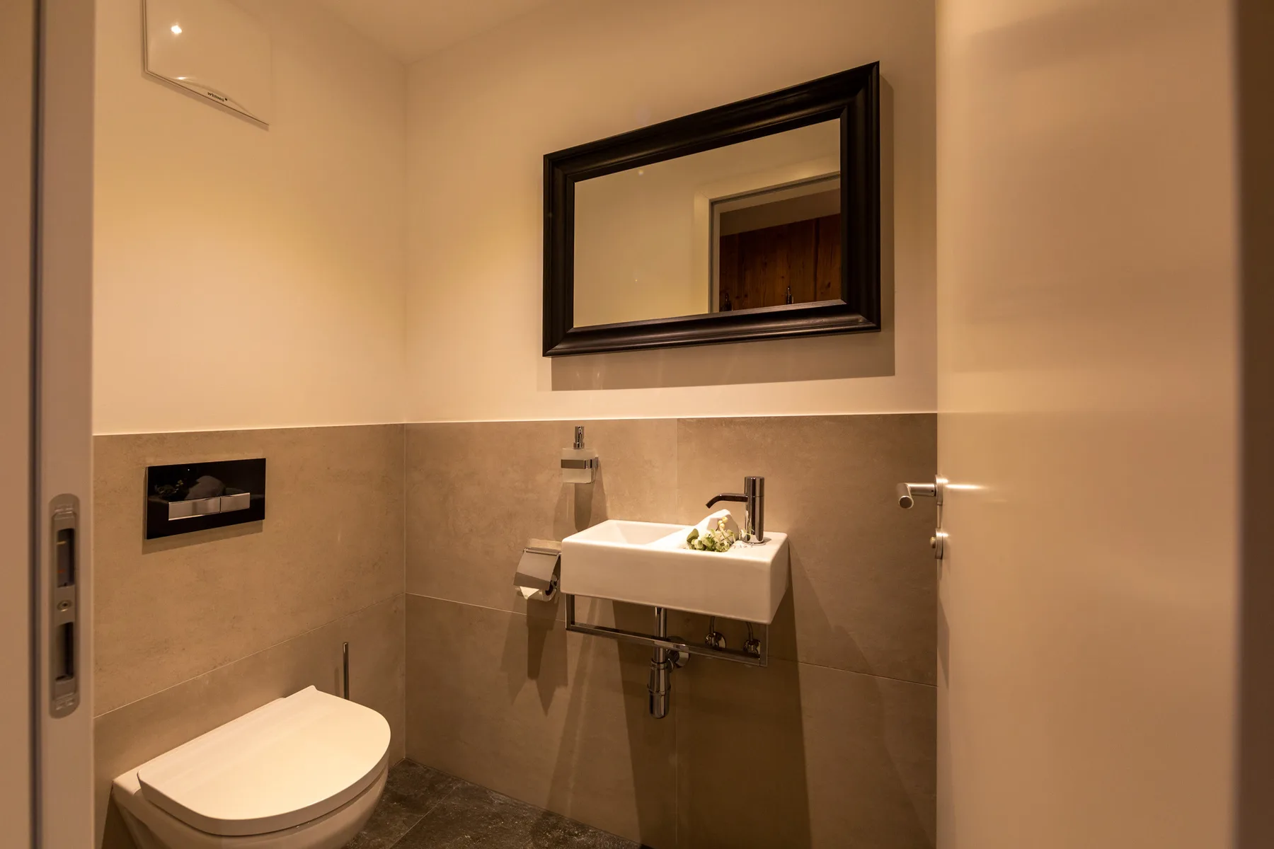 A bathroom with a wall-mounted sink and mirror.