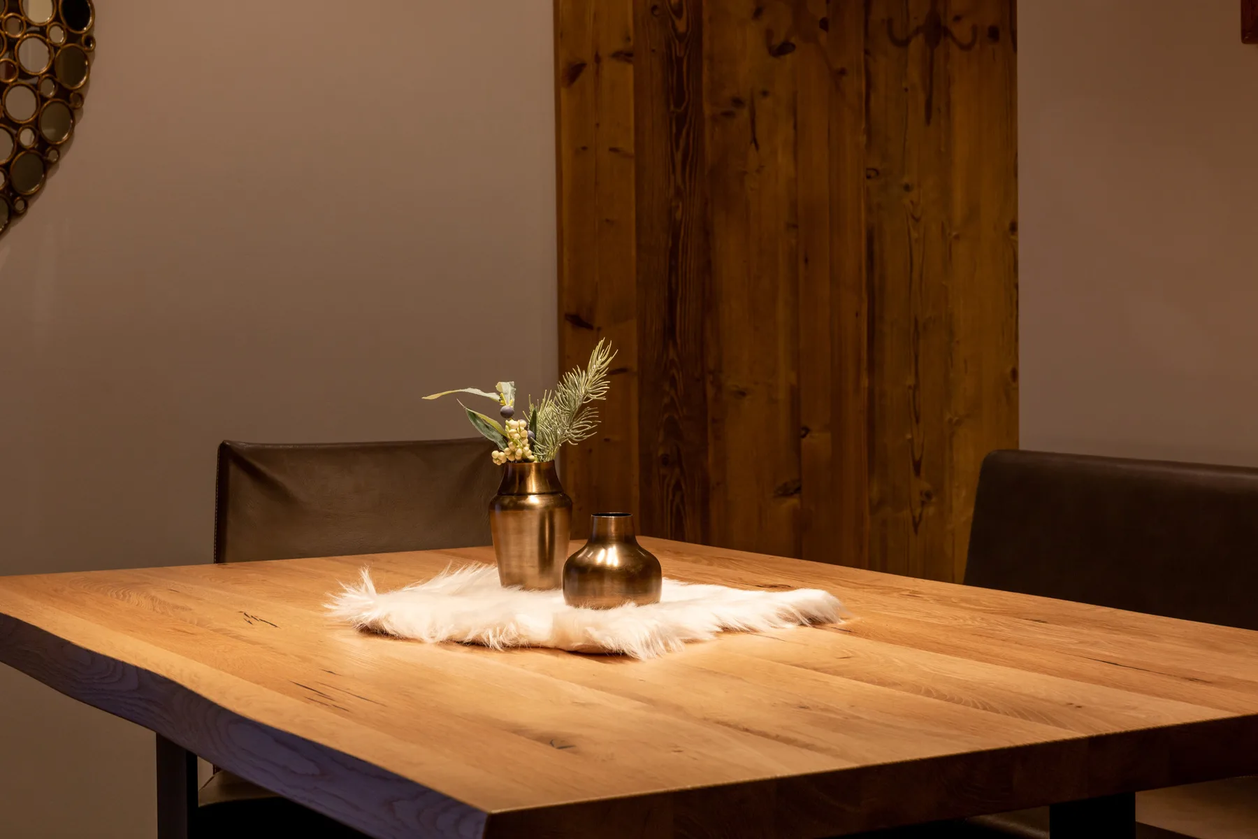 A wooden dining table is decorated with small vases and greenery.