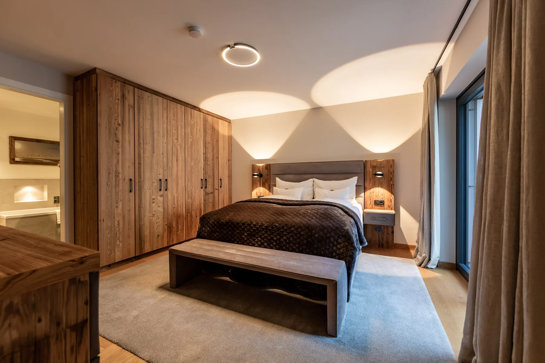 A bedroom with a bed, wooden wardrobes, and a rug.