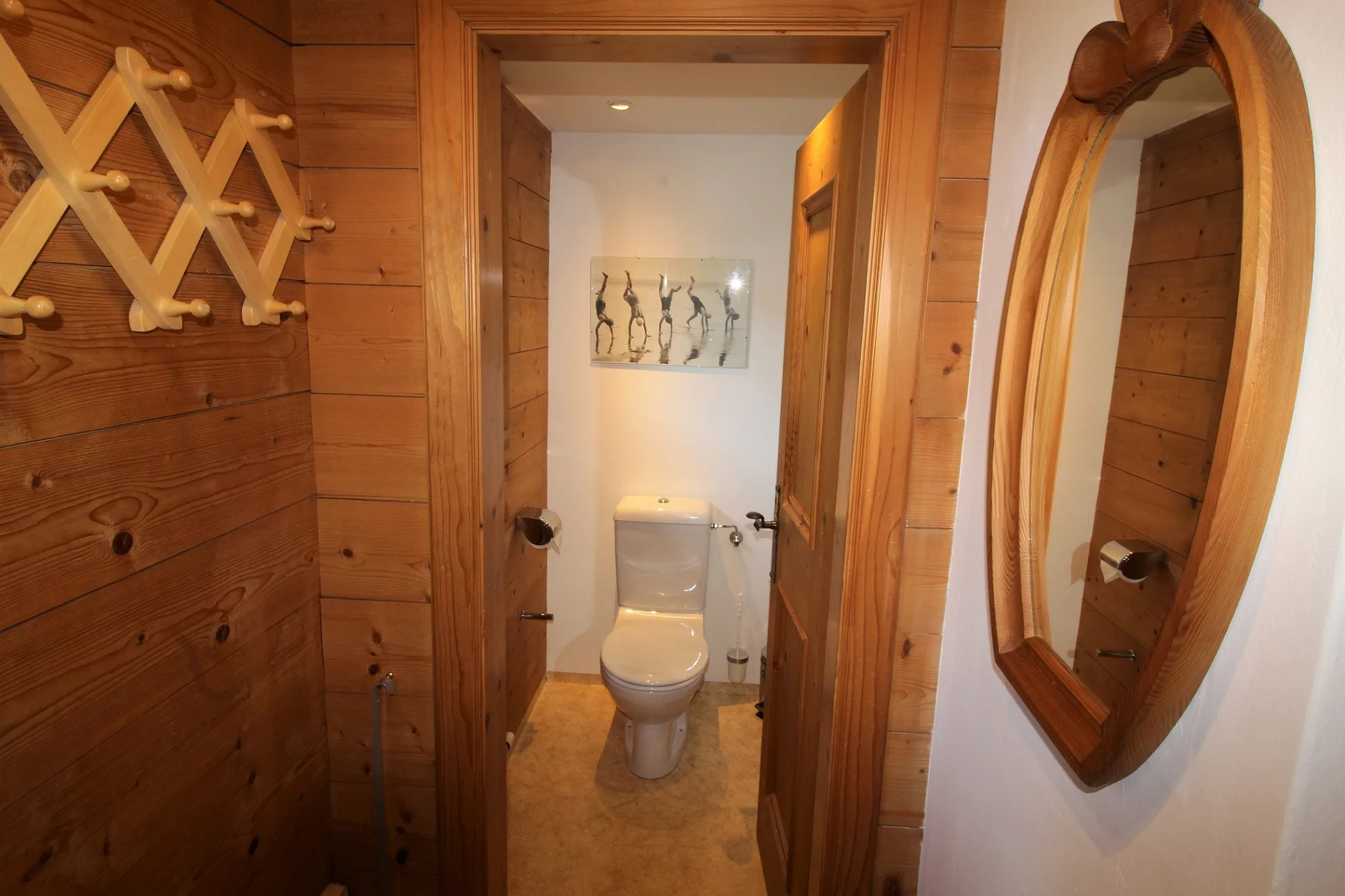 A compact bathroom with a toilet, wood-paneled walls, and a wall mirror.