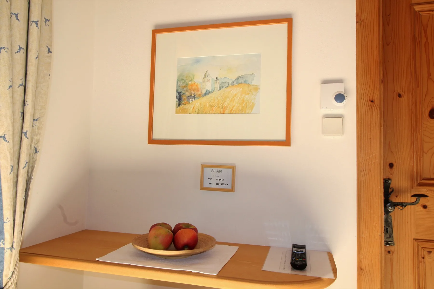 A small table beneath framed artwork holds a bowl of fruit.