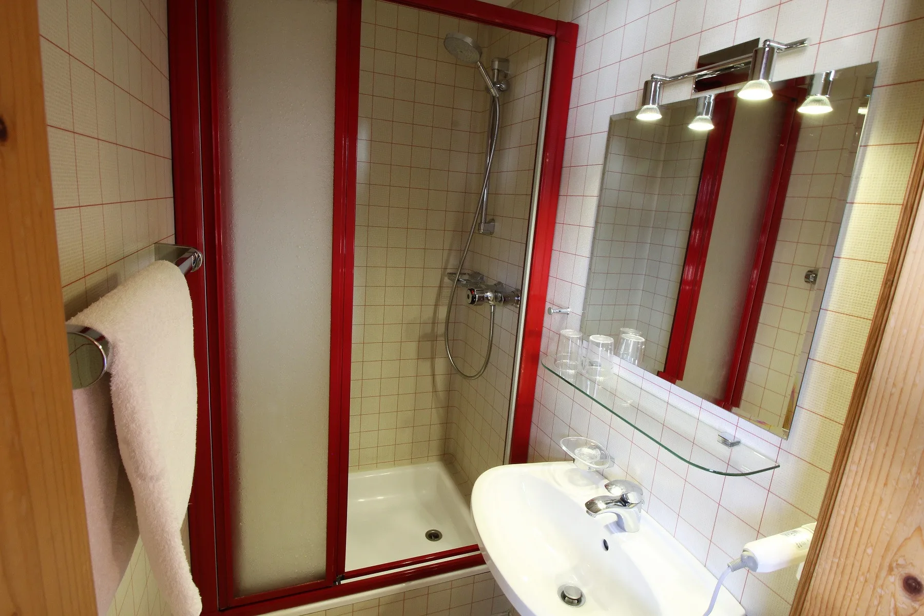 A tiled bathroom with a shower, sink, and wall mirror.