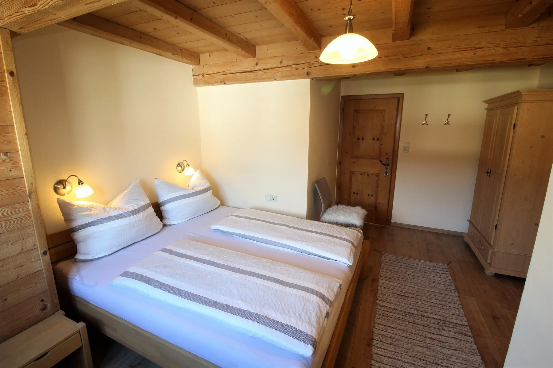 A bedroom with a double bed, wooden ceiling, and wardrobe.
