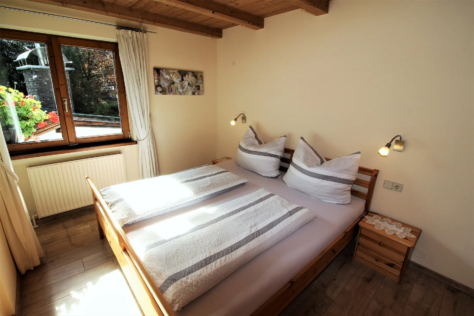 A bedroom with two beds beneath a wood-beamed ceiling.