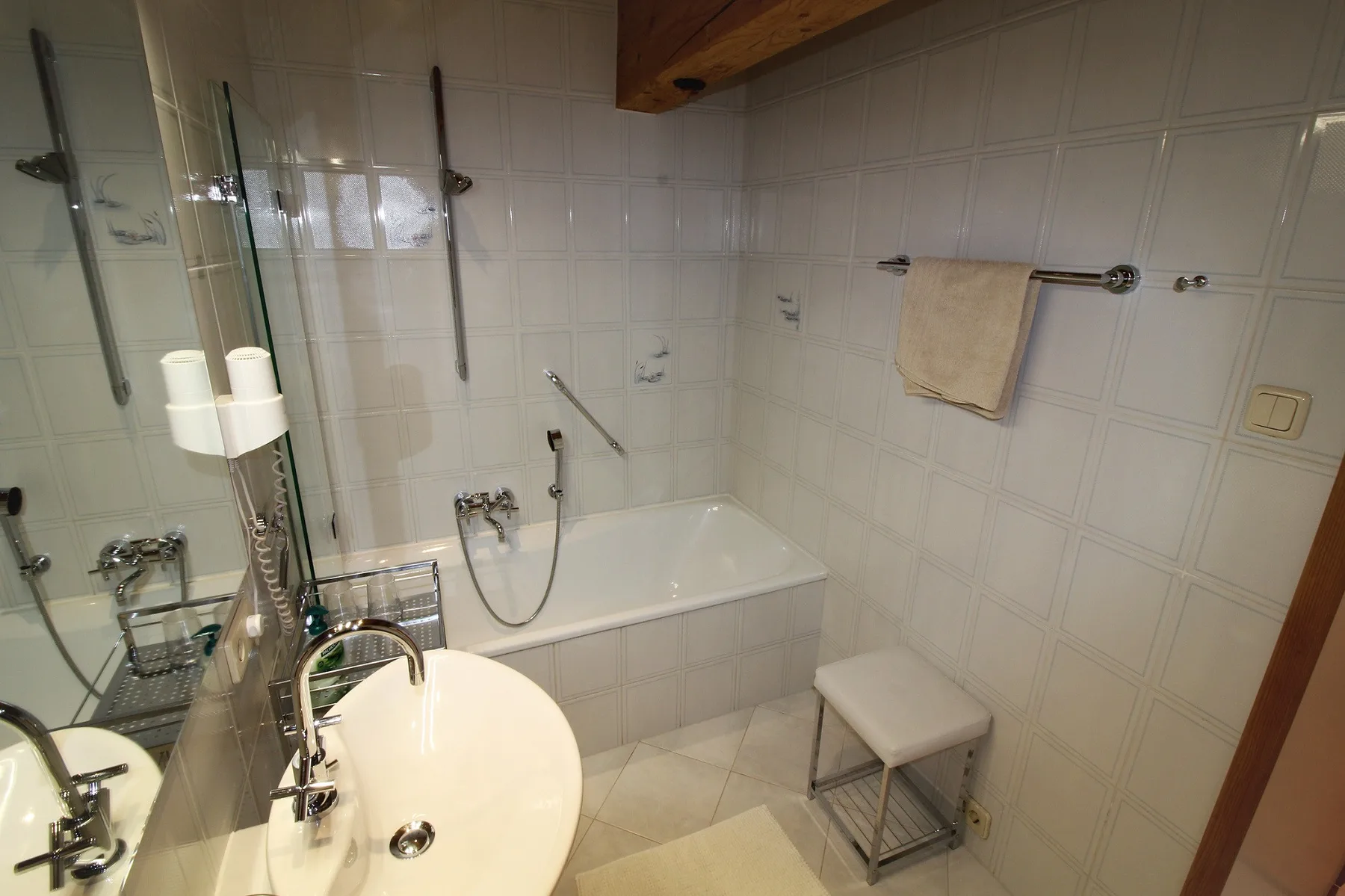 A tiled bathroom with a bathtub, shower fixtures, and a sink.