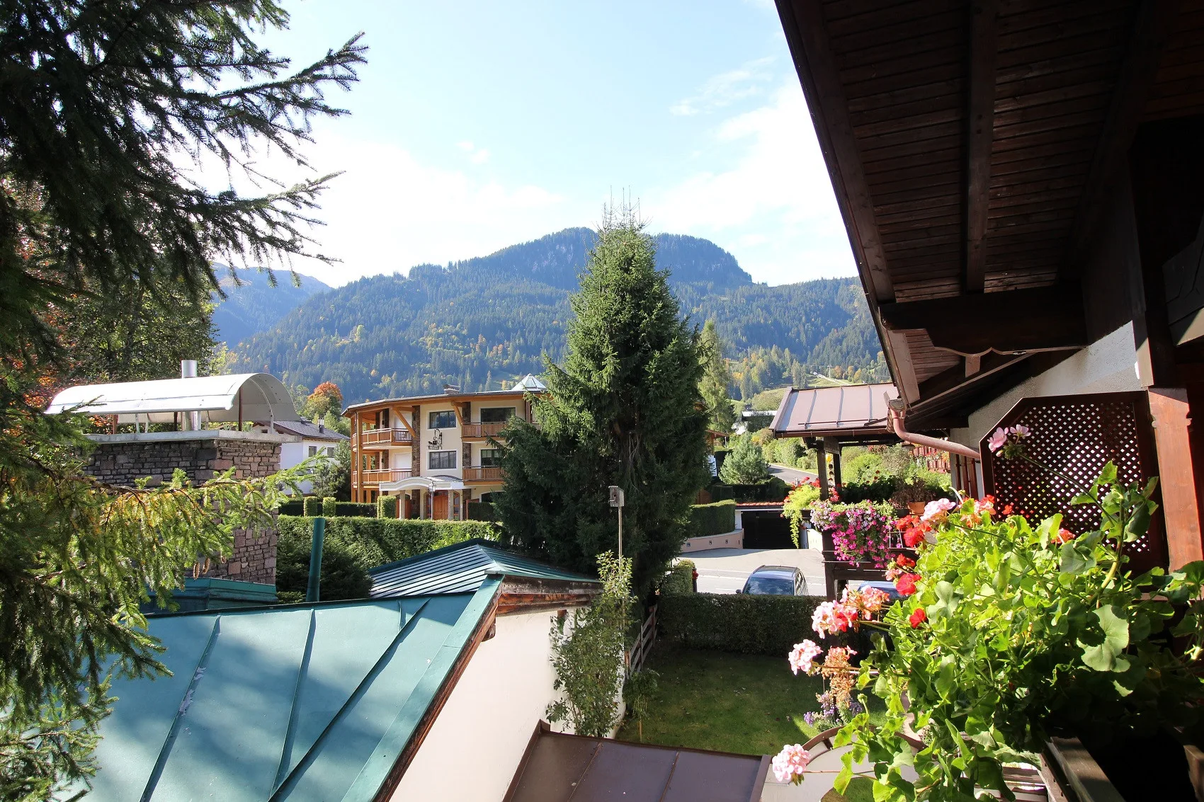 A mountain-view residential scene with balconies, rooftops, and flowering plants.