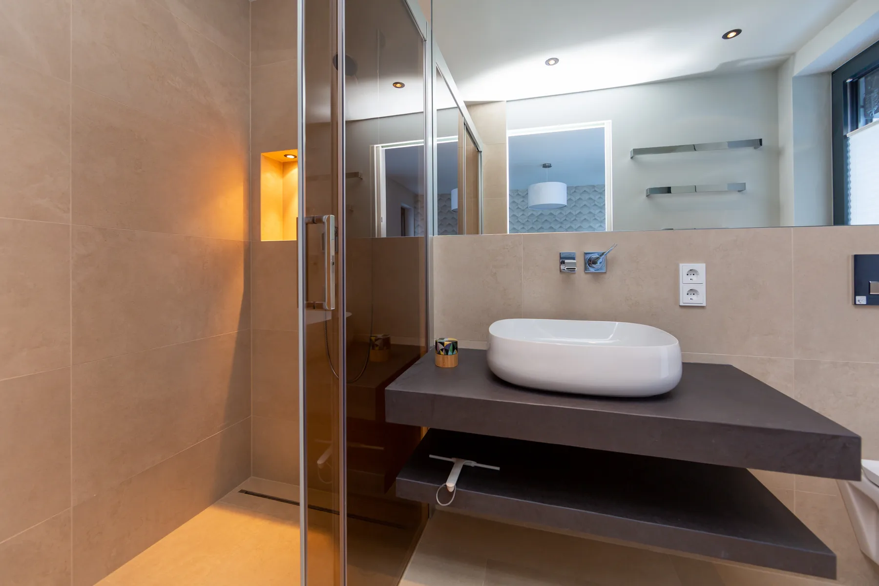 A modern bathroom with a white basin set on a dark vanity.